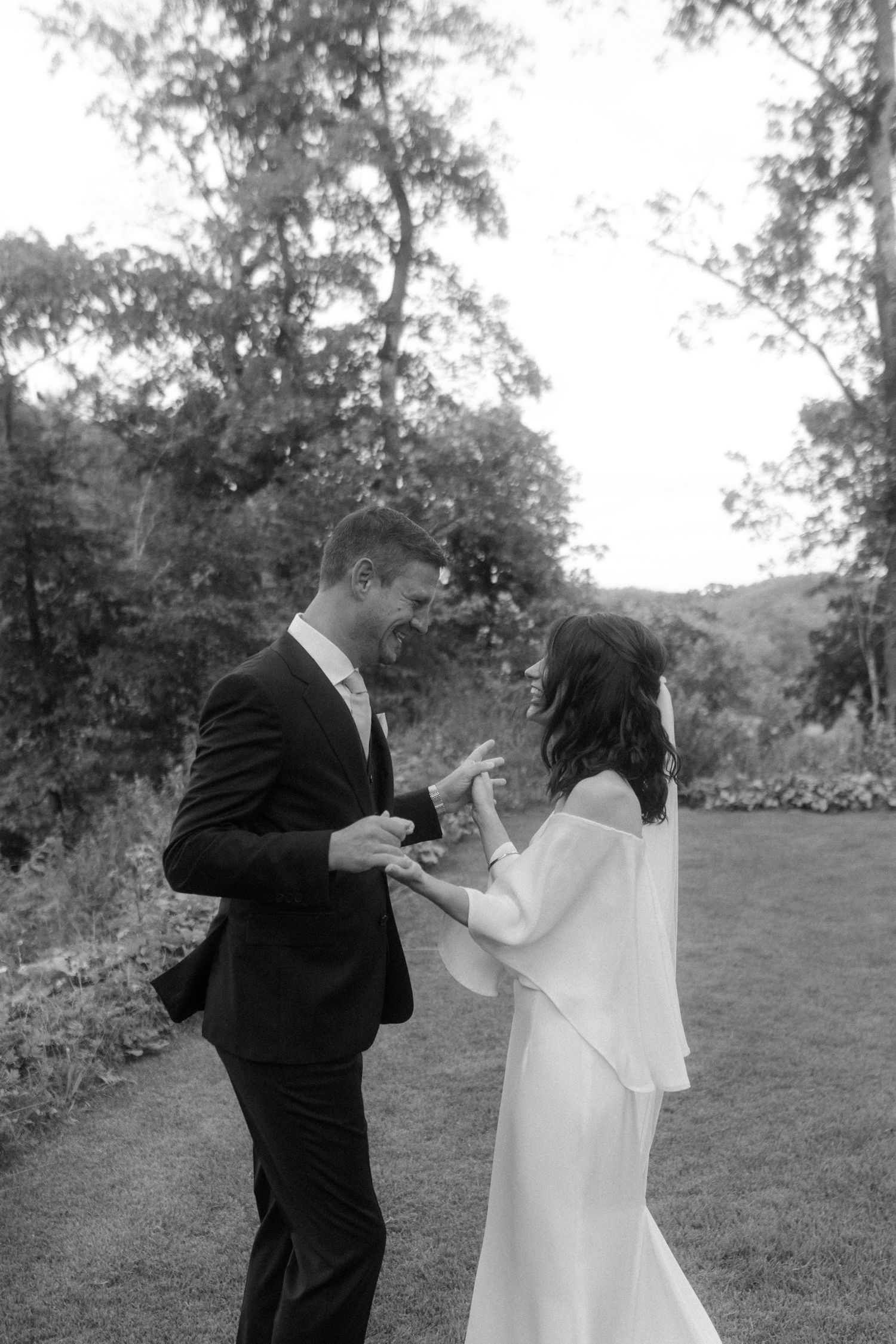 A black and white photo of a couple exchanging rings during their garden wedding ceremony.