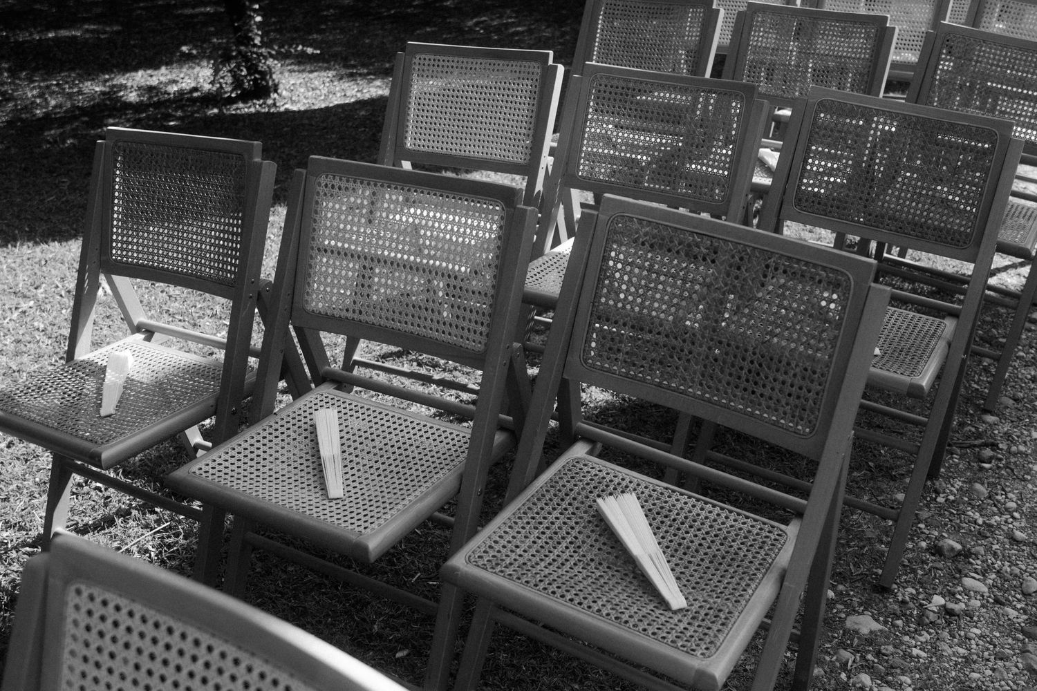 Dark wooden chairs arranged in neat rows for outdoor event.