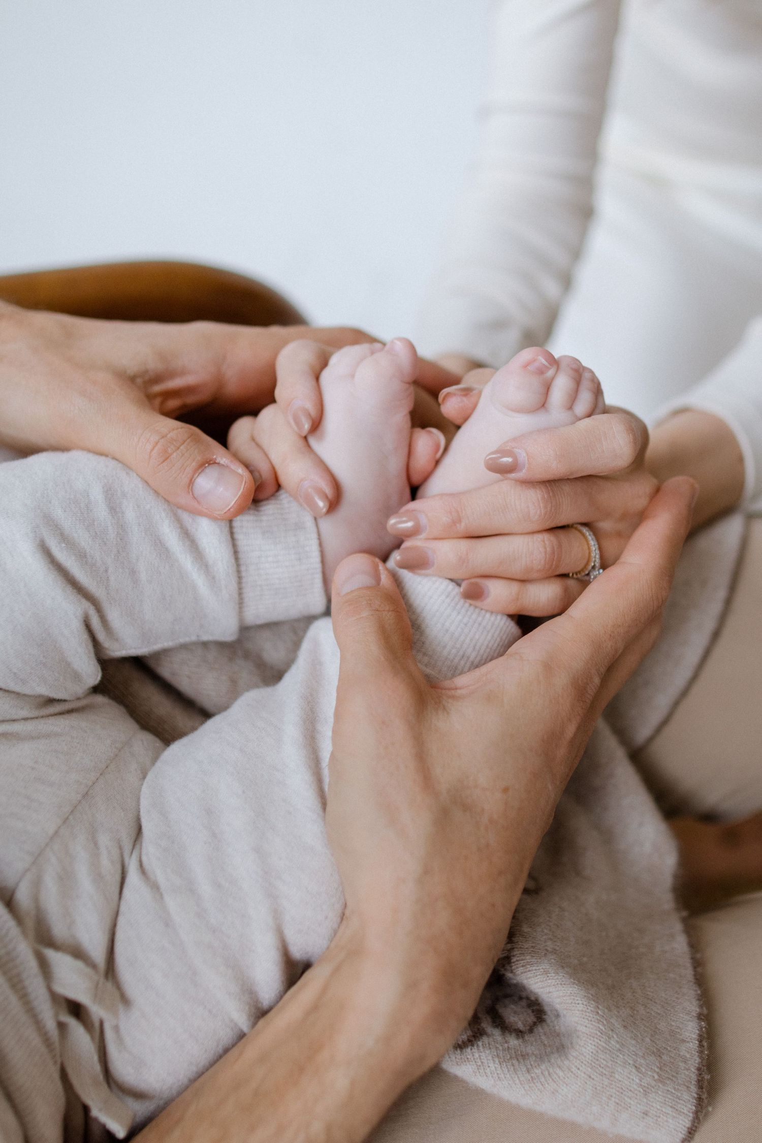 Close-up of hands holding and caressing each other against a light background.
