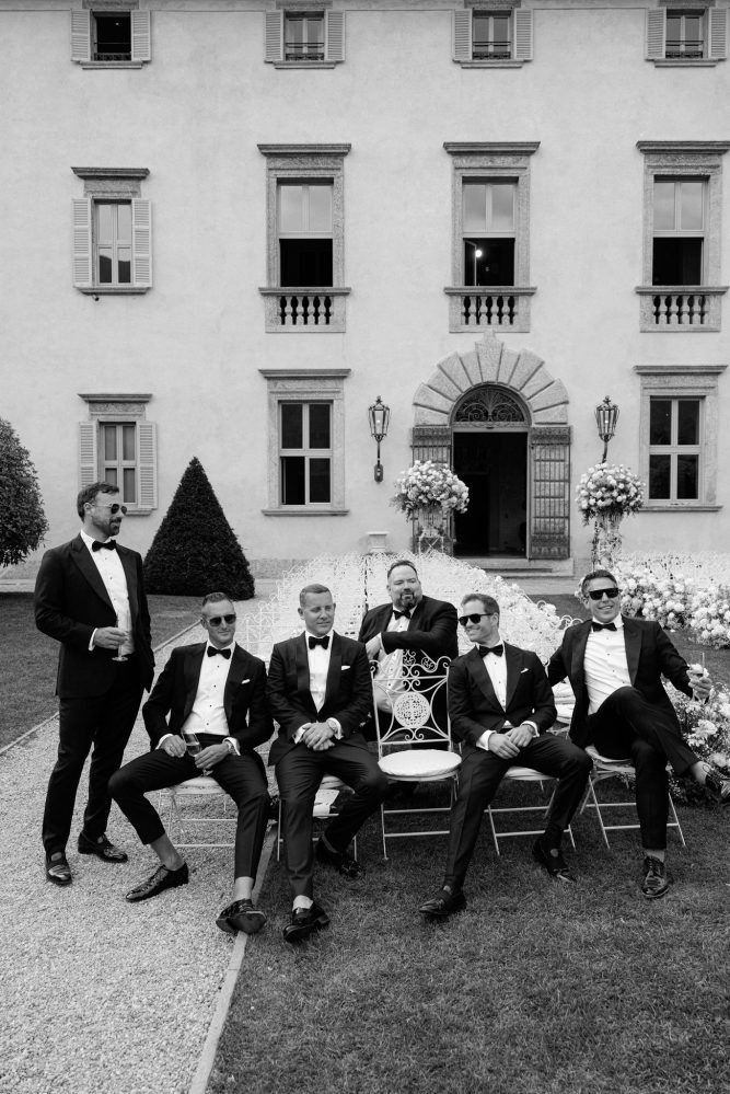 Black and white photo of formal group gathered outside historic building entrance.
