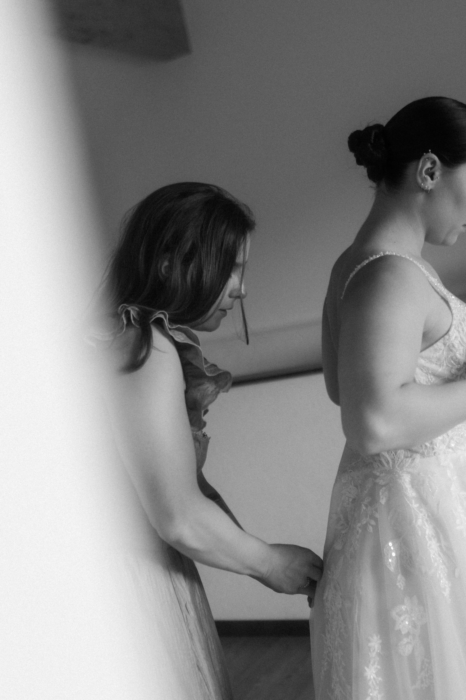 Black and white image showing final adjustments to a wedding dress.