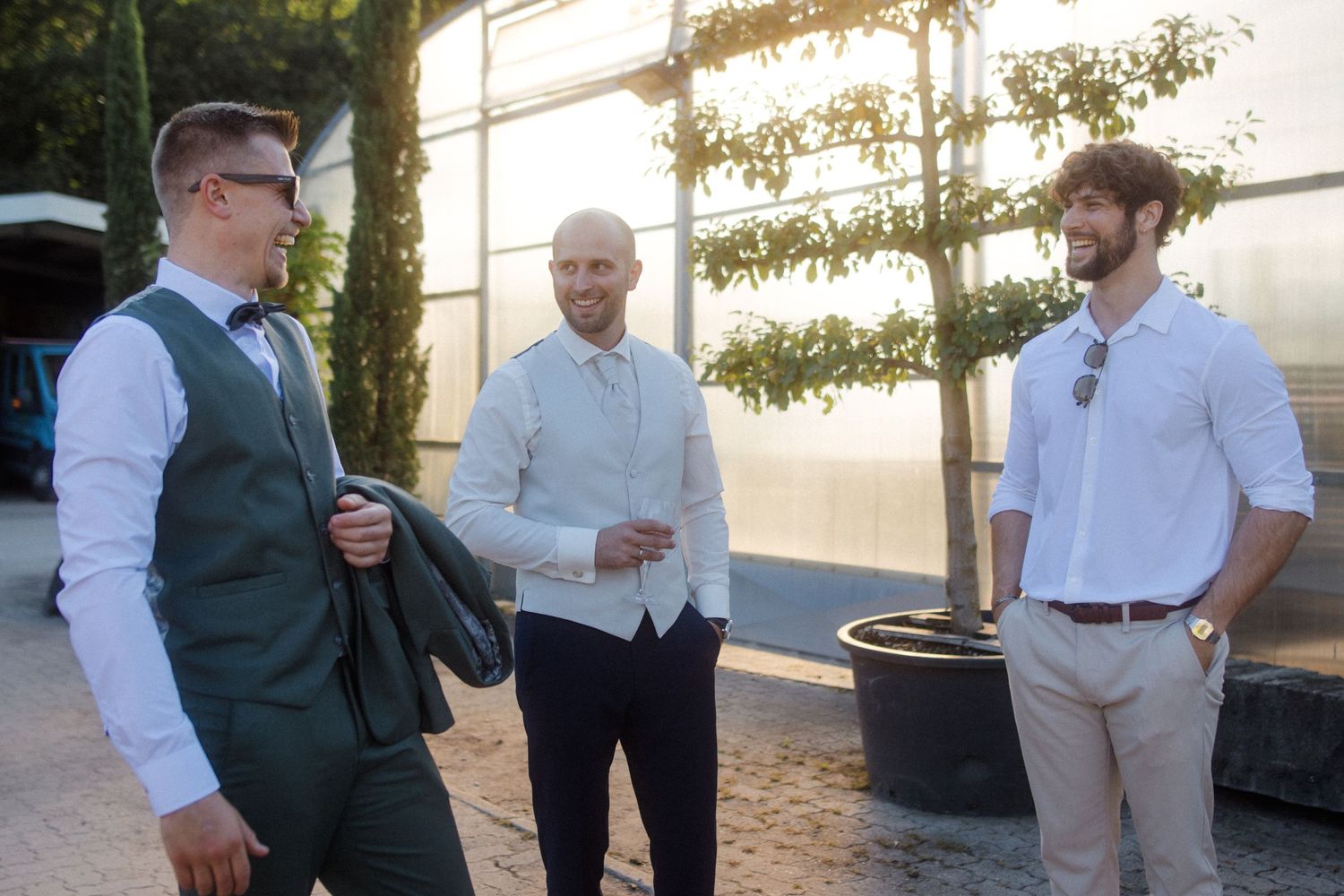 Casual conversation among guests at an outdoor wedding venue during golden hour.