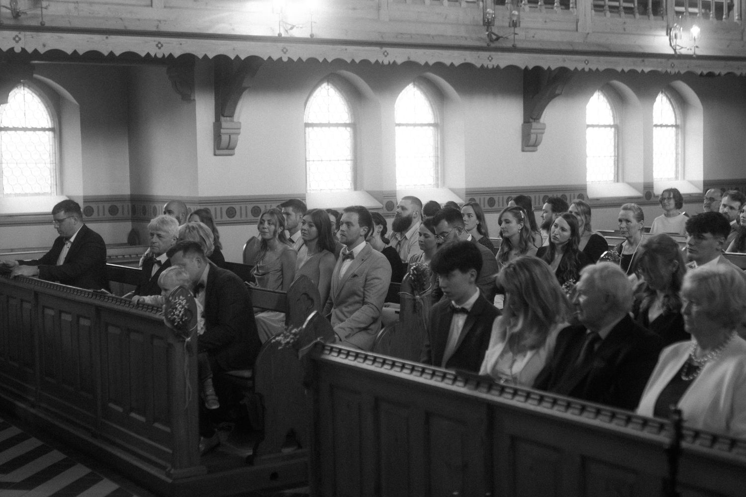Black and white photo of congregation members seated in traditional wooden church pews.