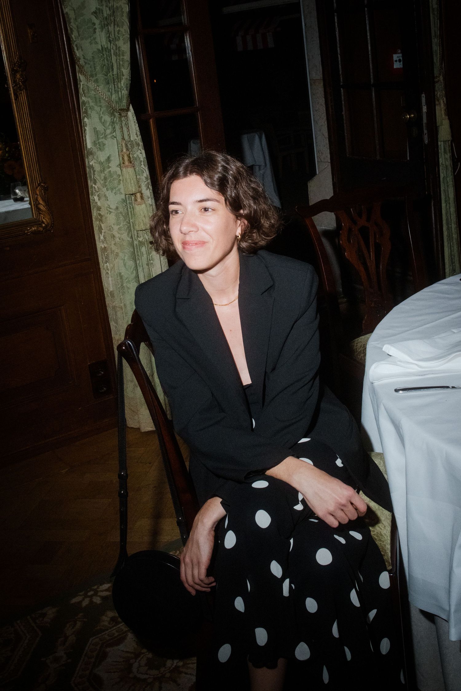 Guest in polka dot dress seated at formal dinner table during evening reception.
