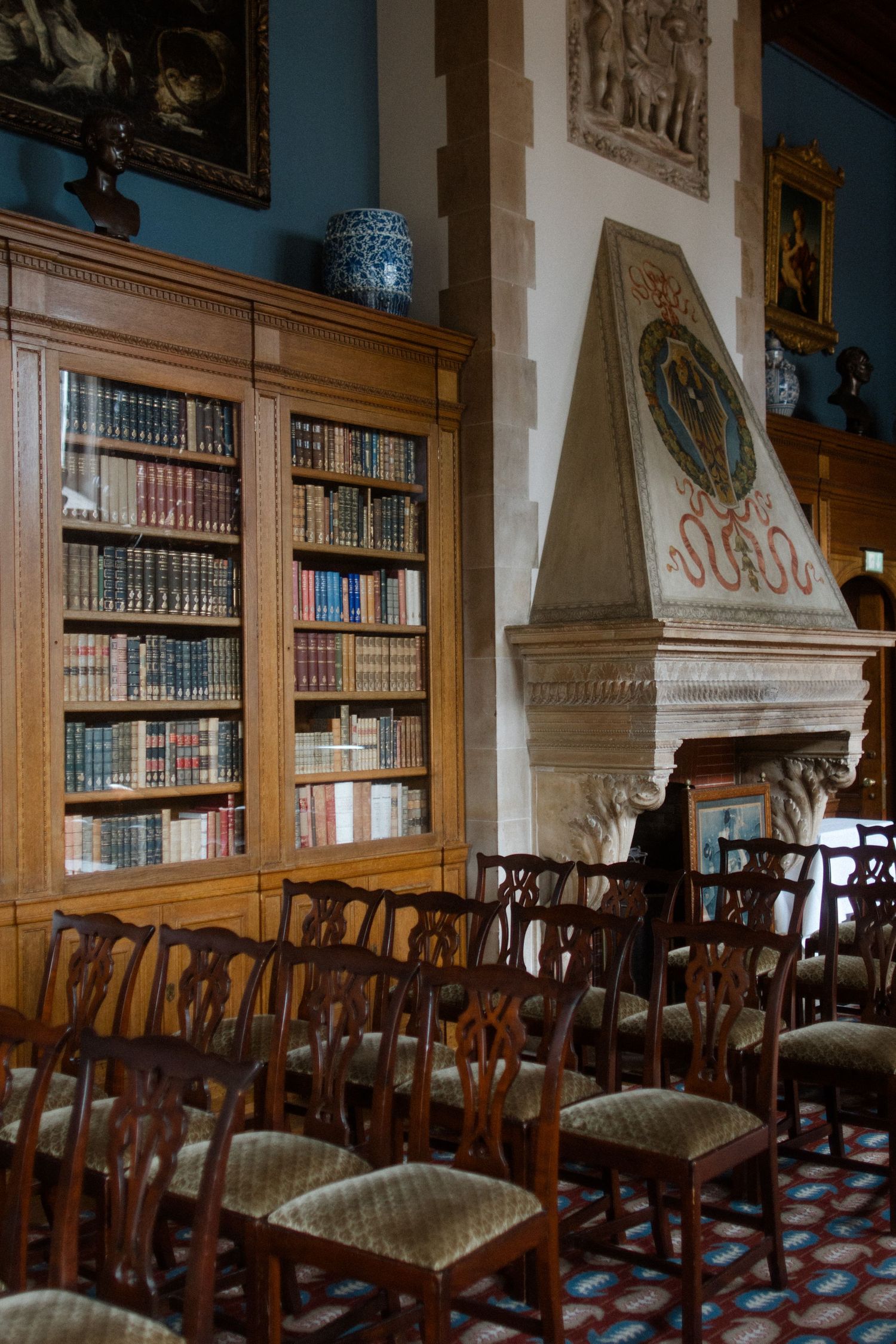 Interior of a historic library with wooden chairs and ornate bookshelves.