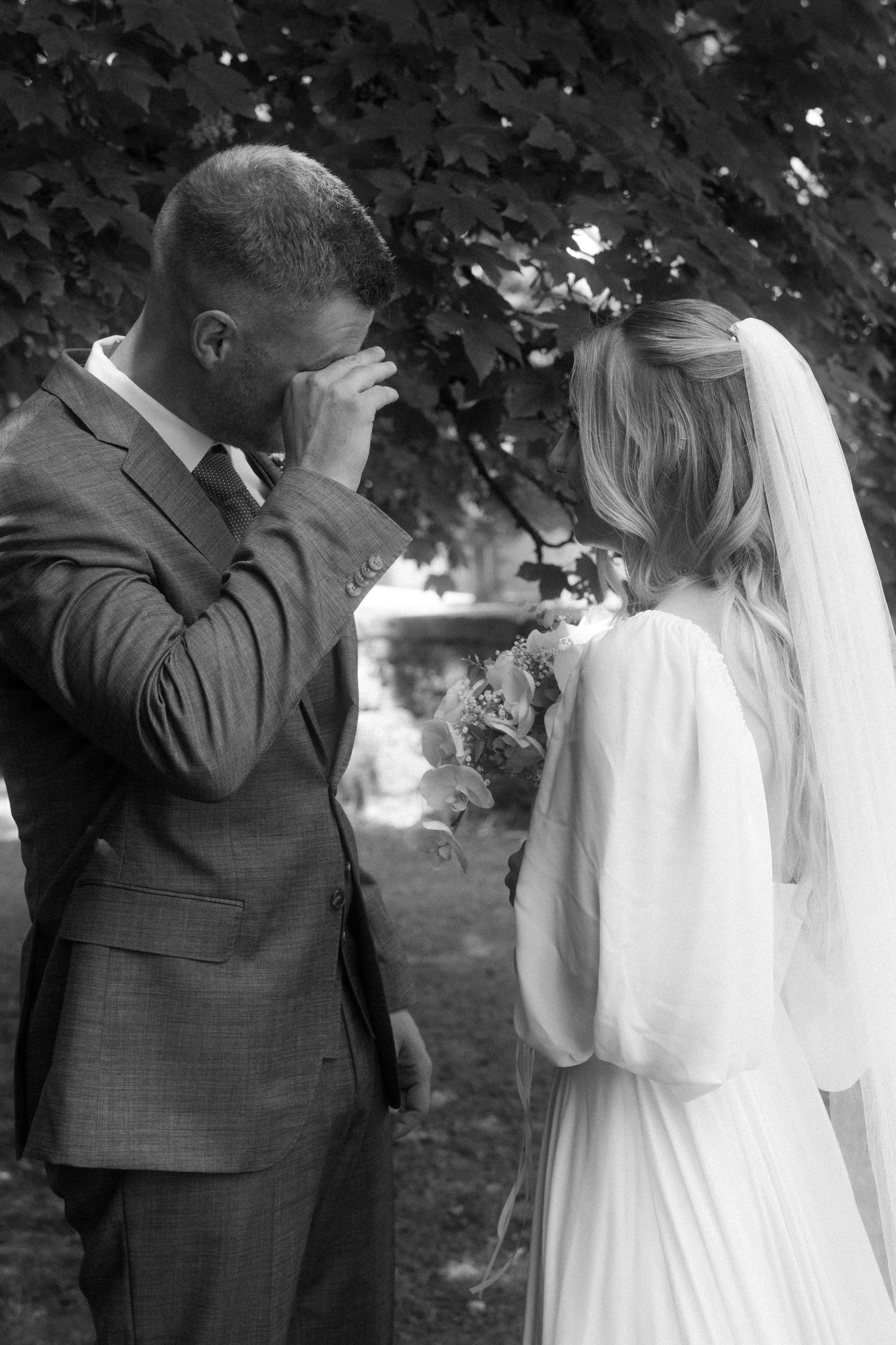 Black and white wedding photos showing an emotional first look moment outdoors.