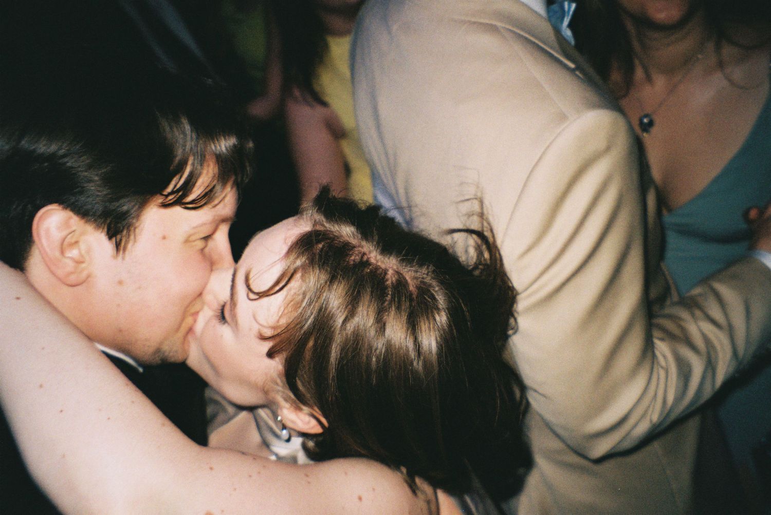Two people sharing a kiss at a lively social gathering or party event.
