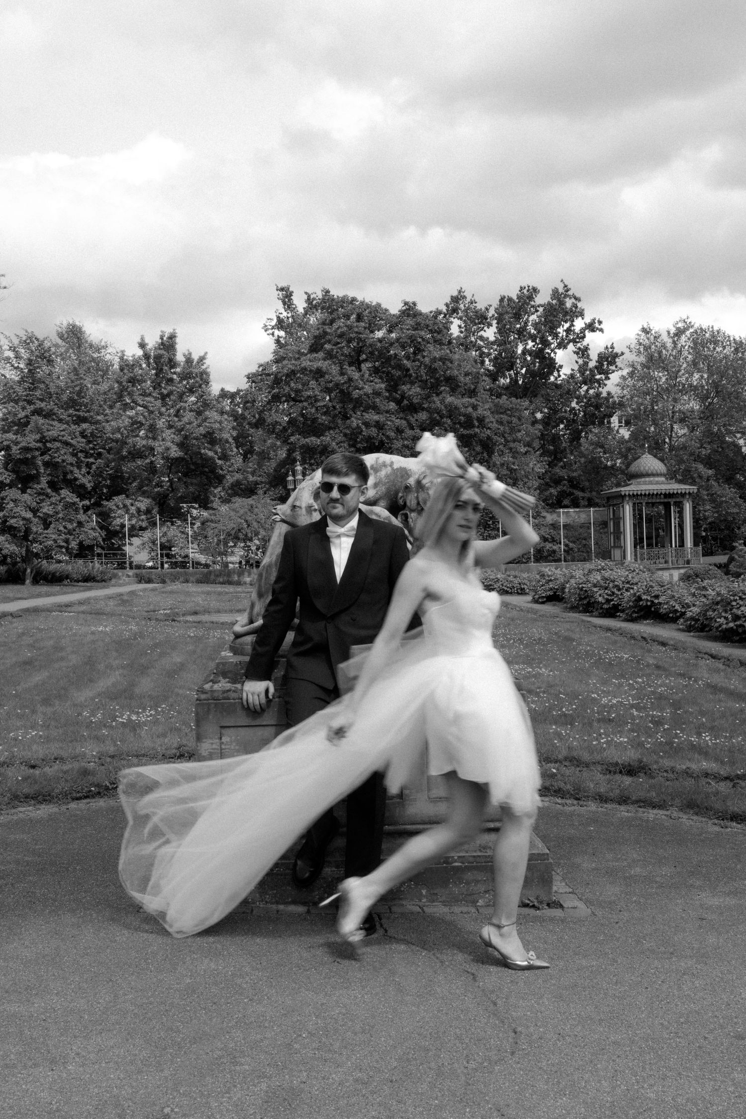 Dynamic black and white photo of dancing newlyweds in garden setting.