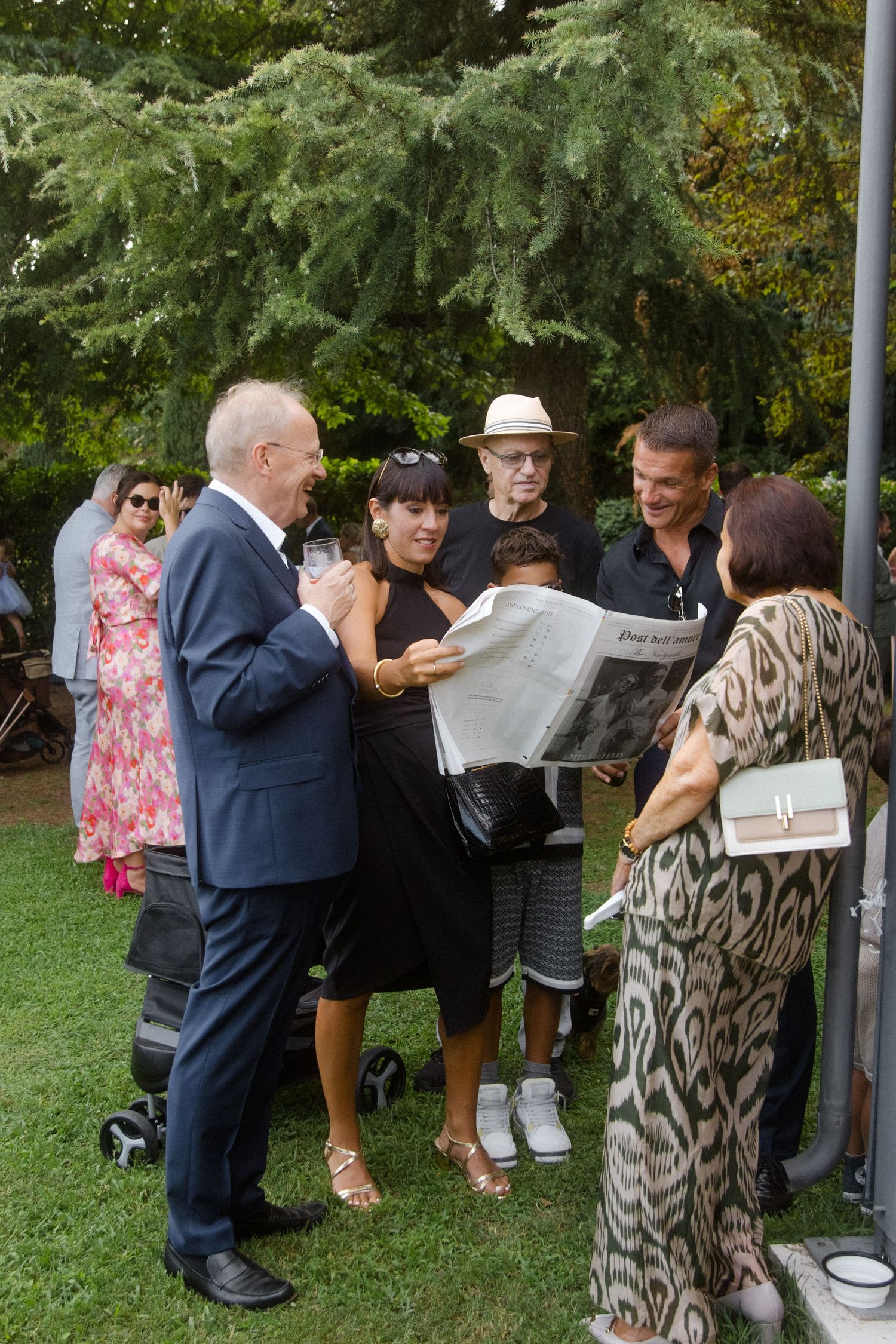 Wedding guests gathered under a canopy viewing documents during an outdoor celebration.