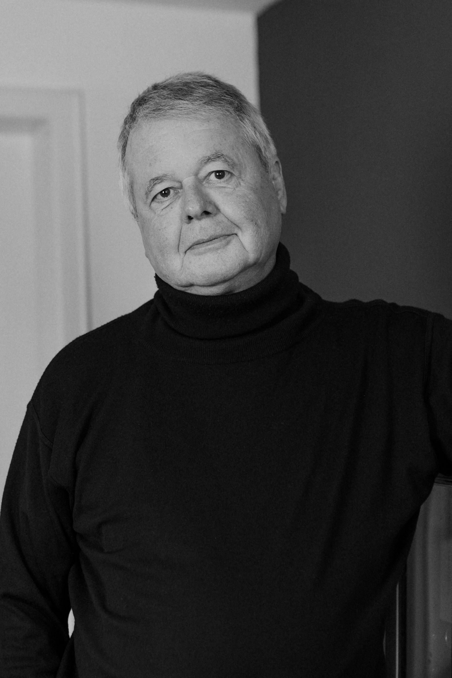 Series of dramatic black and white portraits showing someone wearing a black turtleneck against dark background.