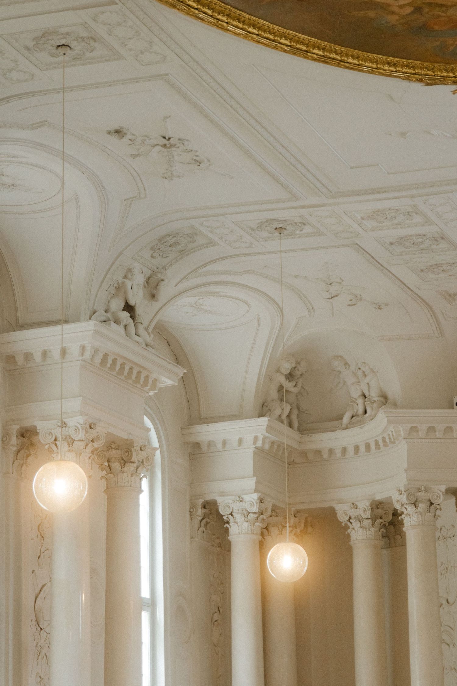 Architectural detail of ornate white ceiling with decorative moldings and classical columns.