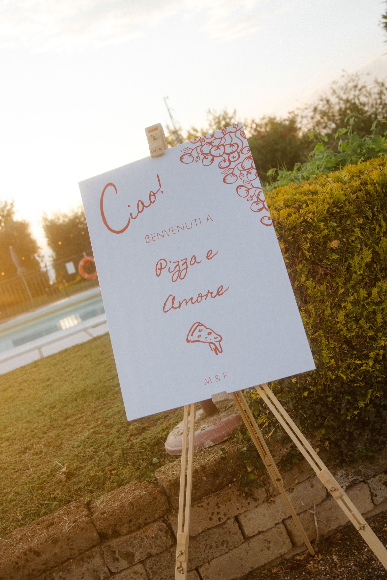 Wedding sign for Pizza e Amore displayed on easel at sunset.