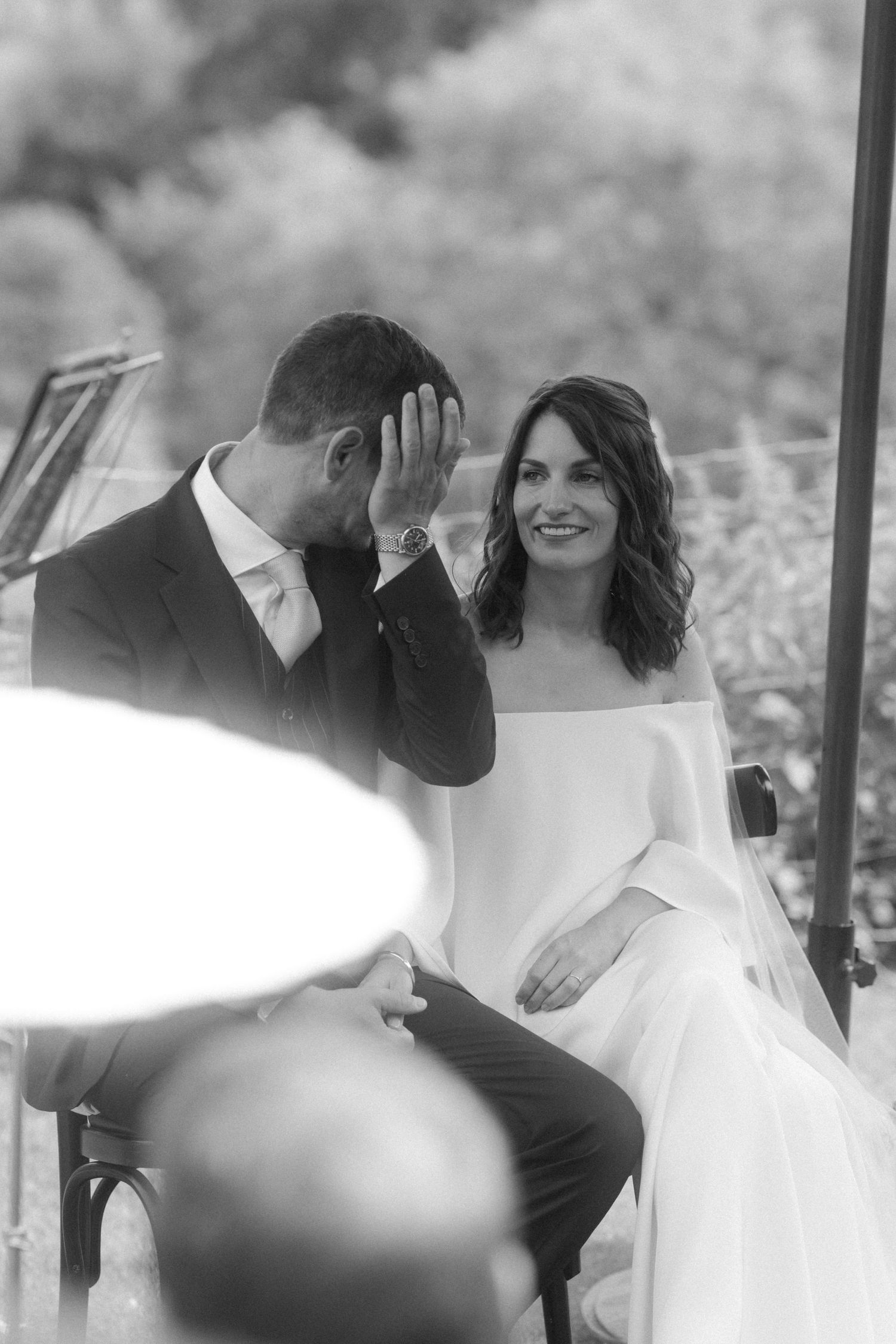 Black and white portrait of bride and groom sharing emotional moment during ceremony.