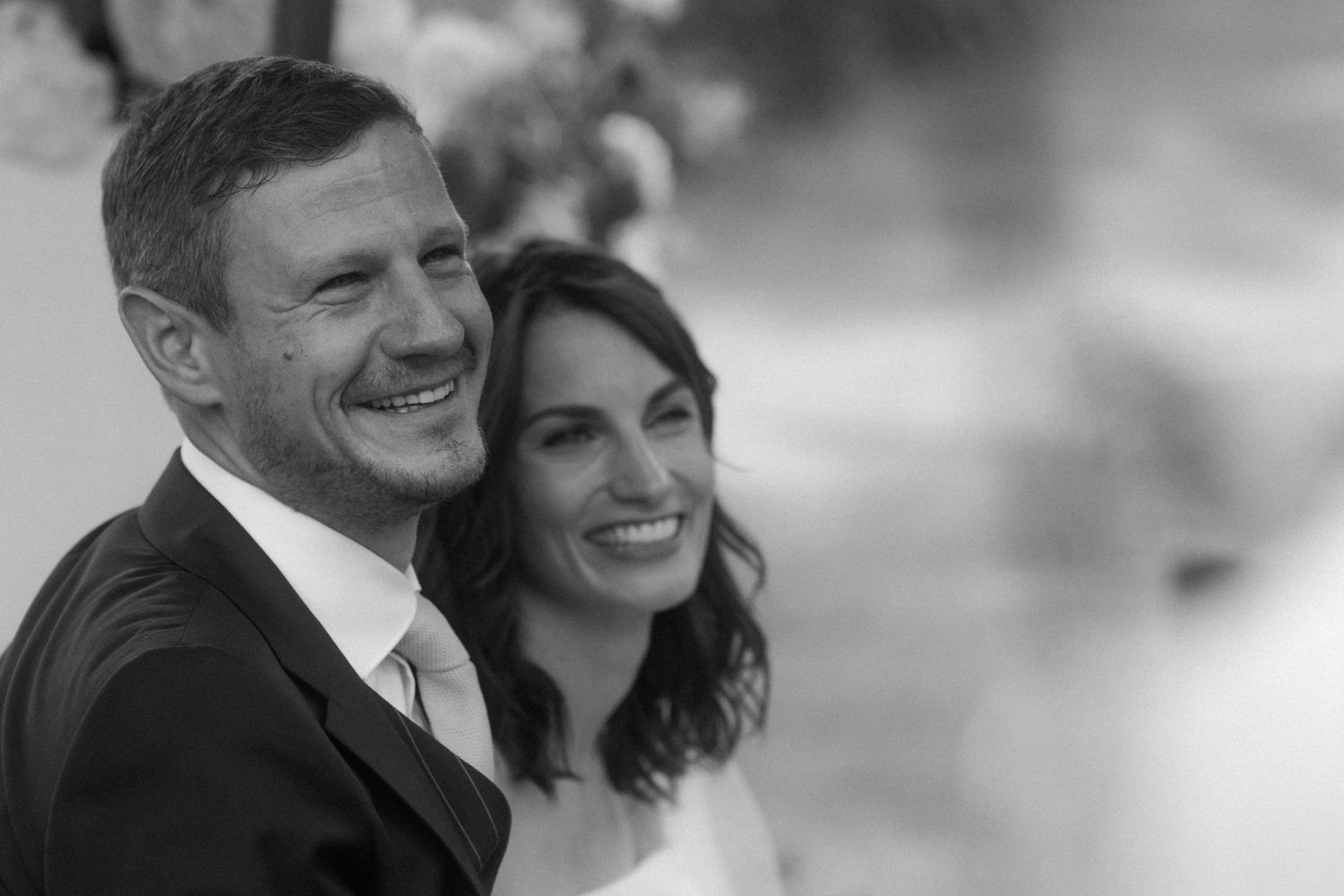 A joyful black and white portrait of newlyweds smiling together on their wedding day.