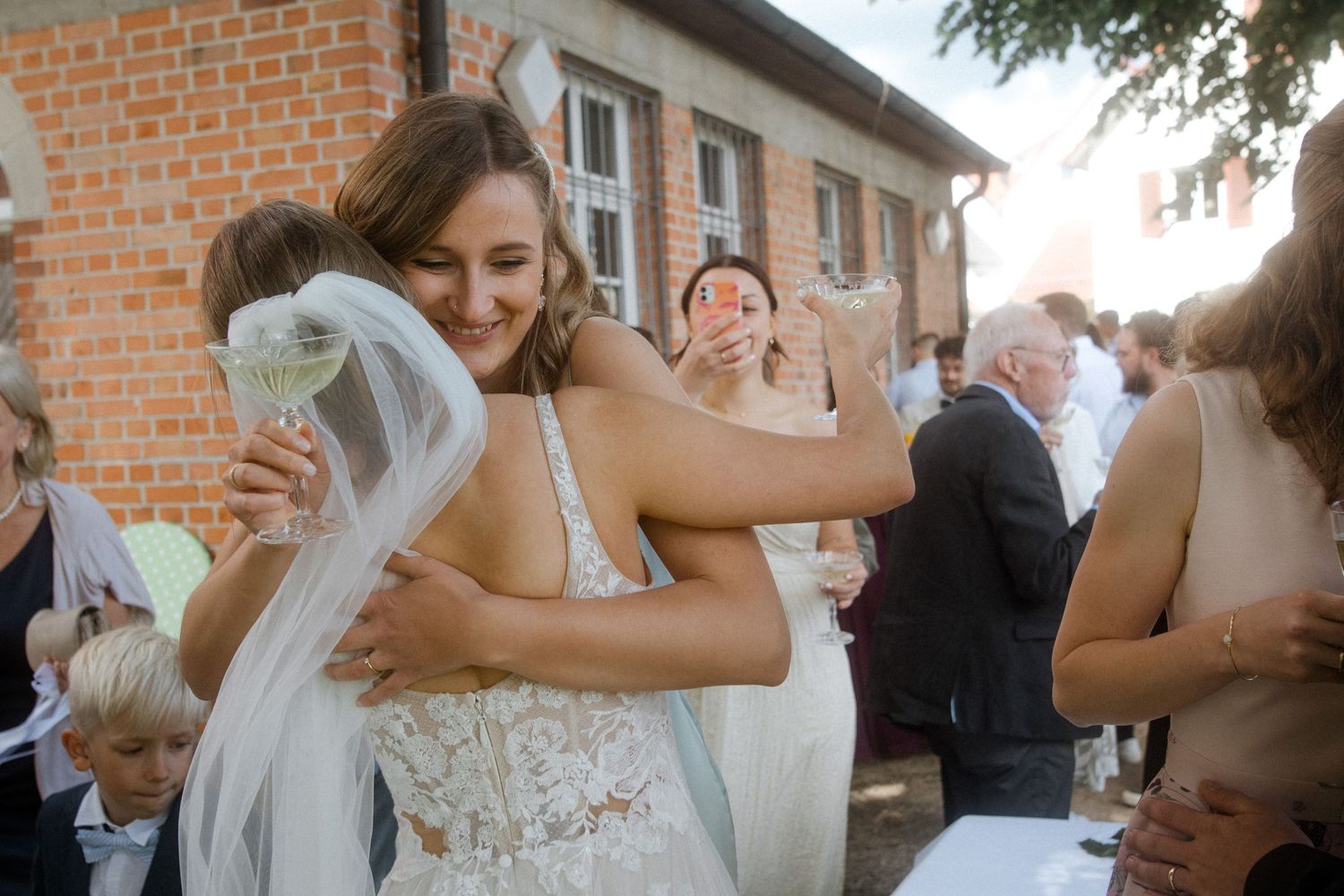 Emotional moment at outdoor wedding reception with guests embracing.