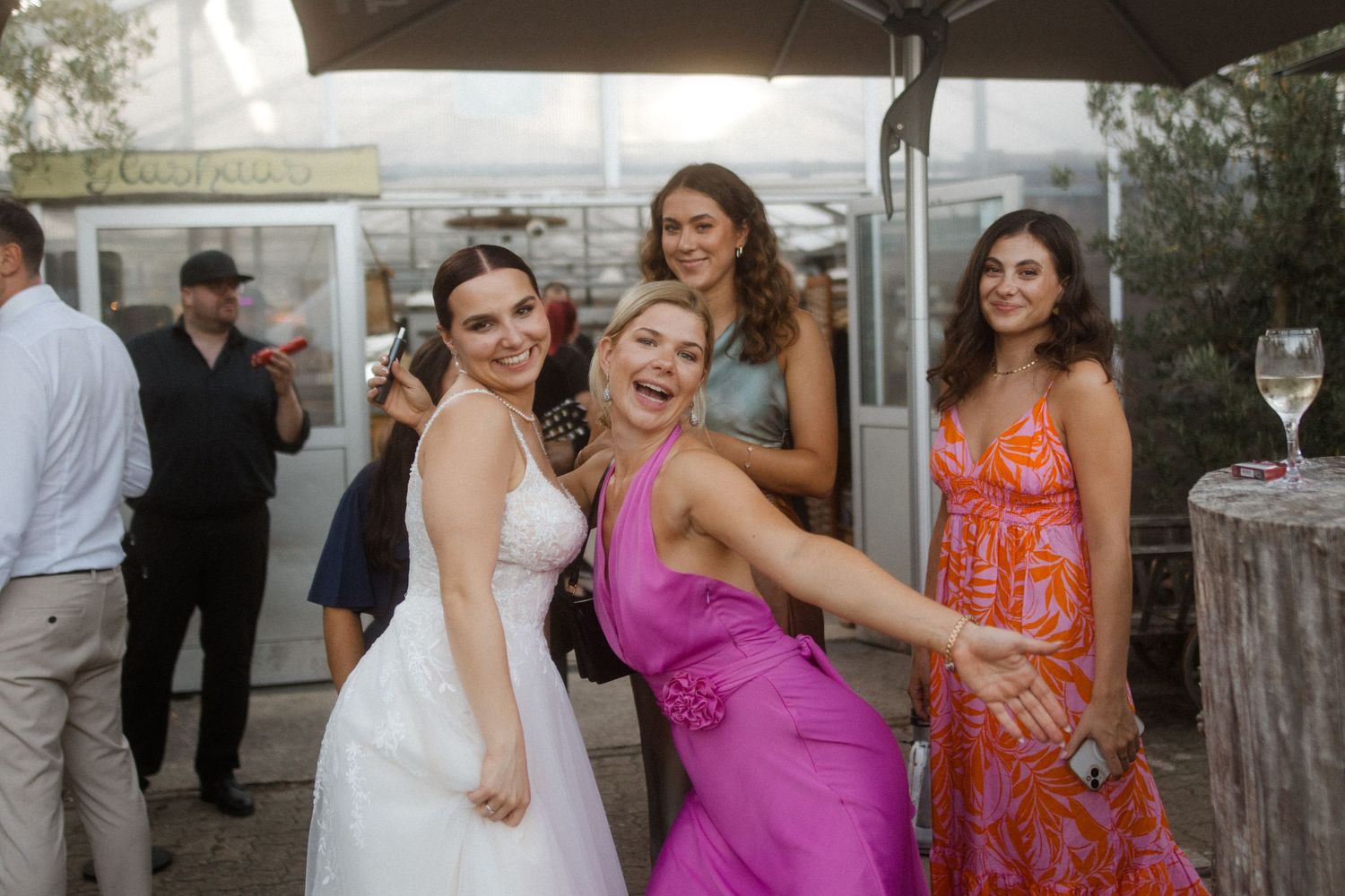 Wedding guests in formal attire sharing laughter during an outdoor reception.