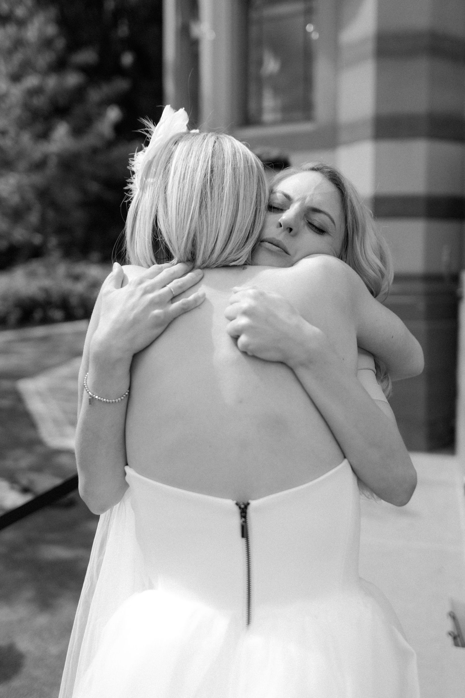 A black and white photo showing two people sharing a tender embrace at a wedding celebration.