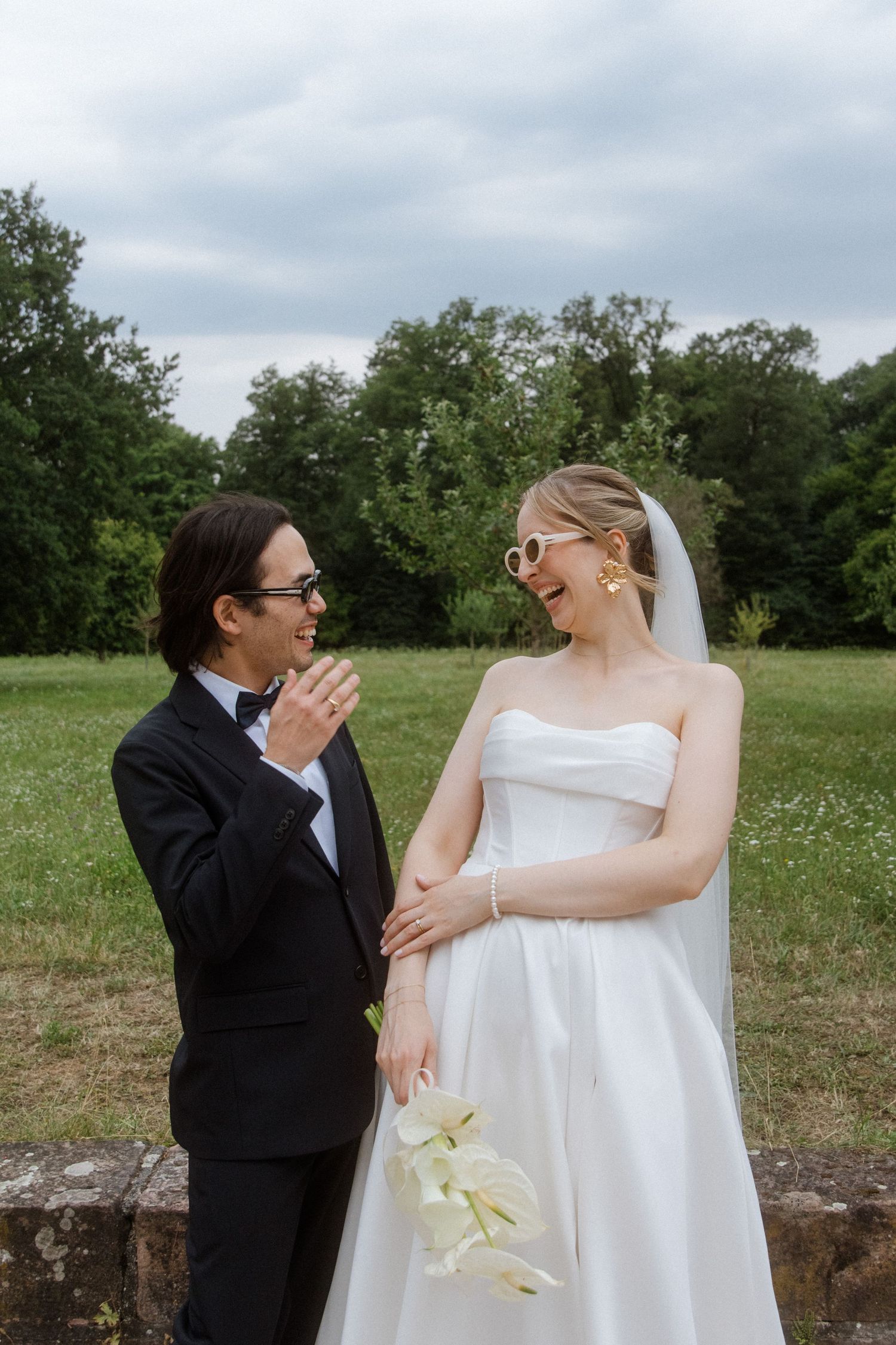 Couple shares a joyful moment together in their wedding attire in an outdoor setting.