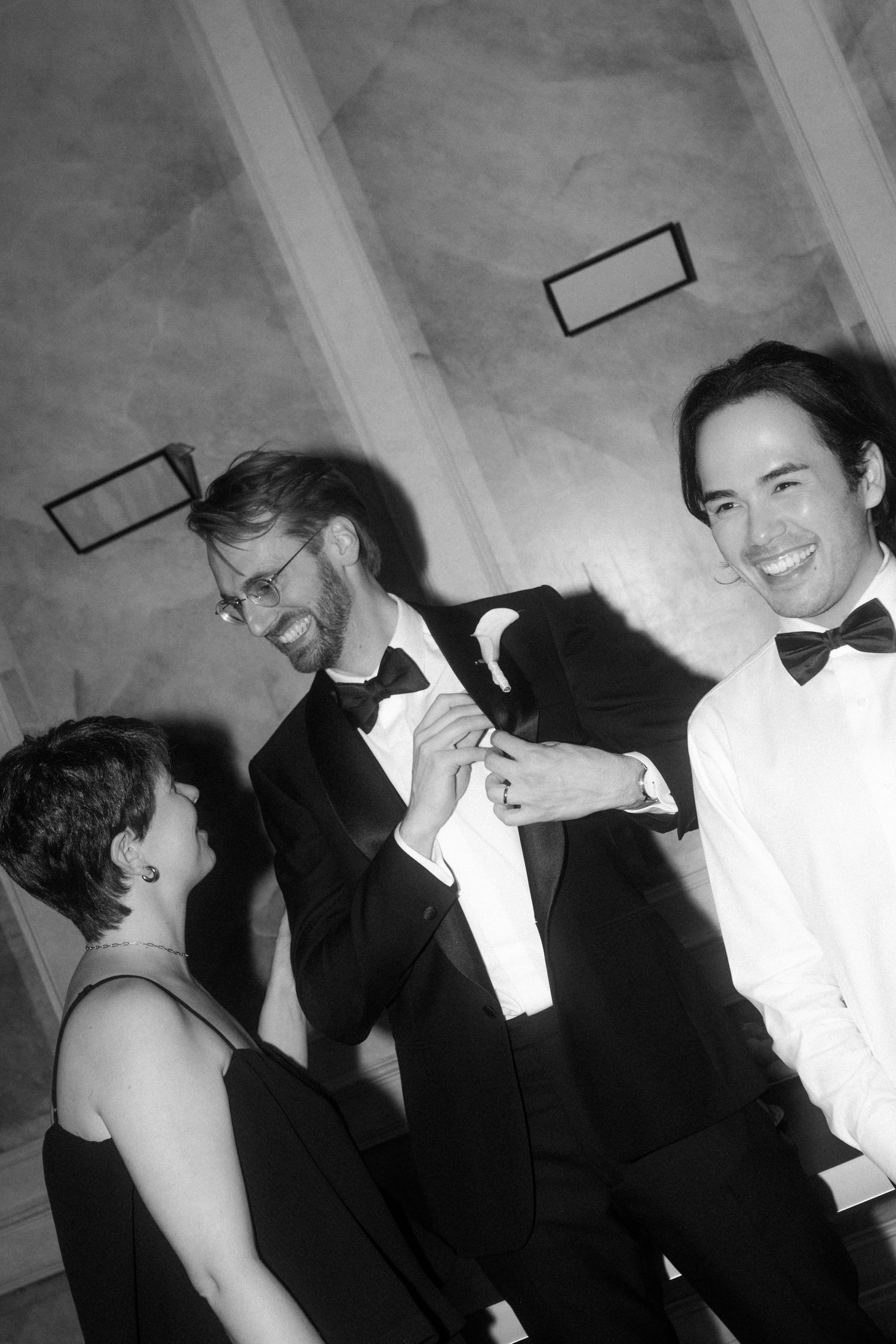 Black and white candid photo of wedding guests laughing together.