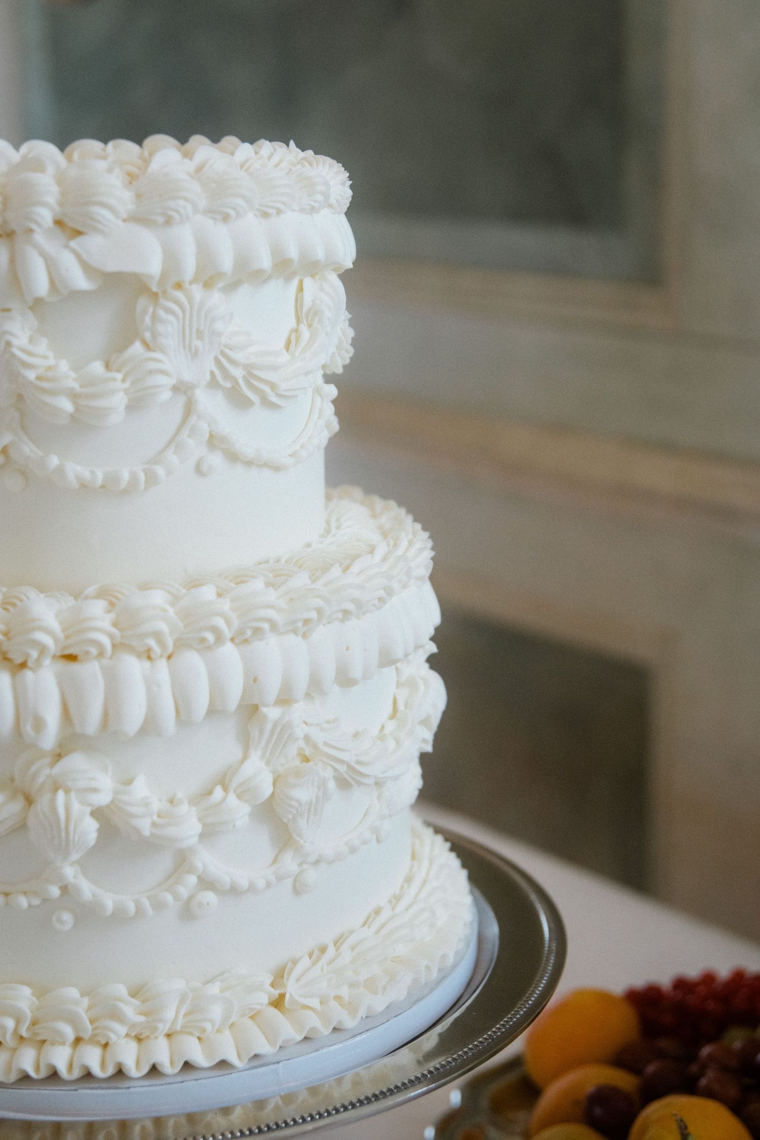 Close-up of a white wedding cake with intricate piped frosting details.