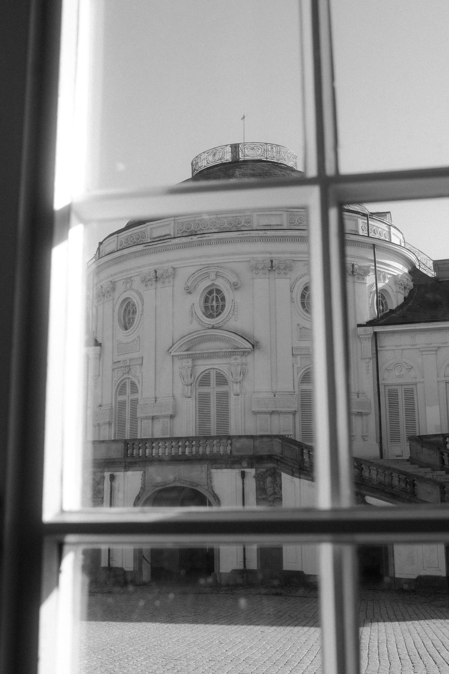 View of classical palace architecture through window panes in black and white.