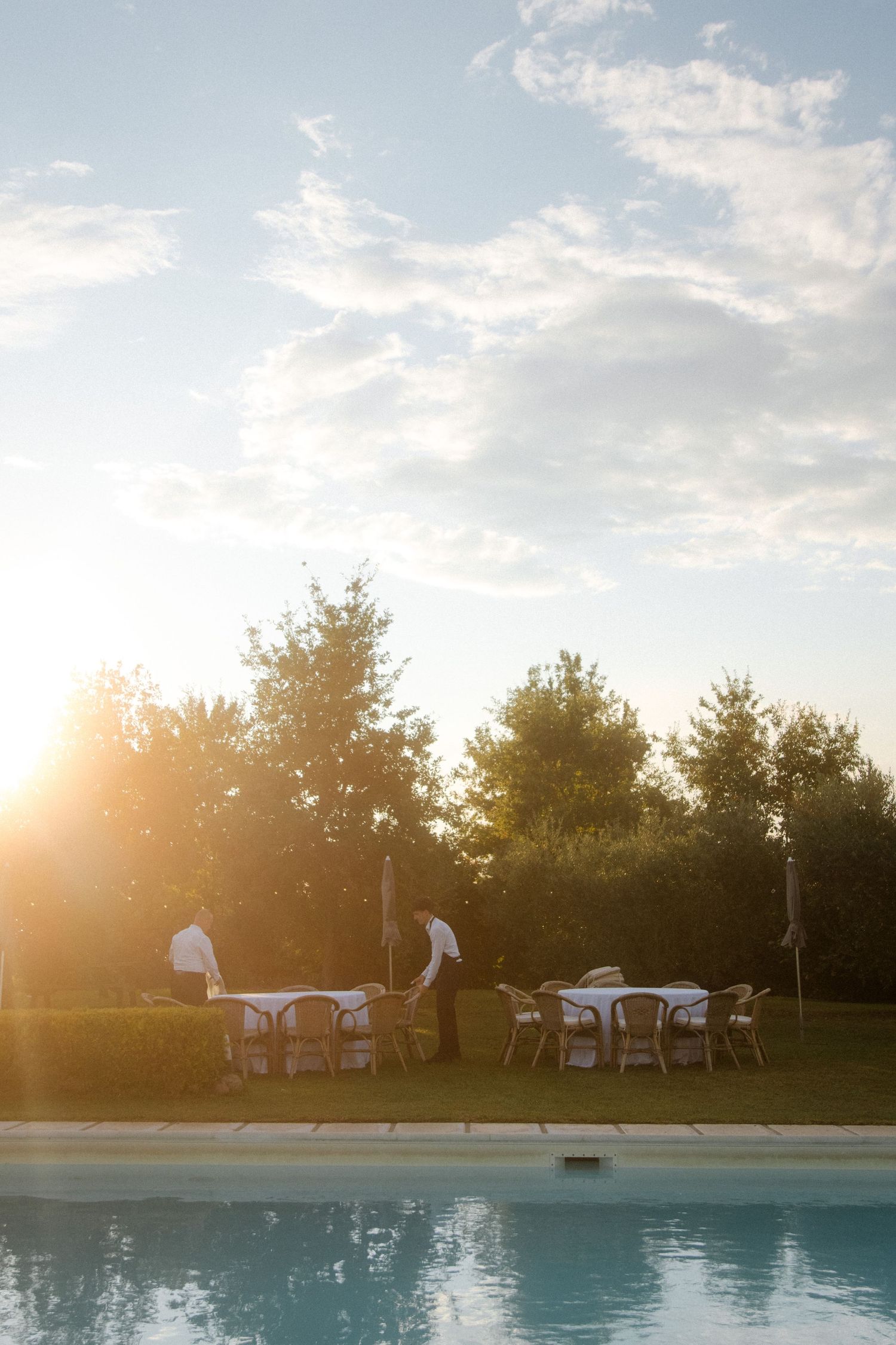 Pool side event setup during golden hour with tables and chairs.