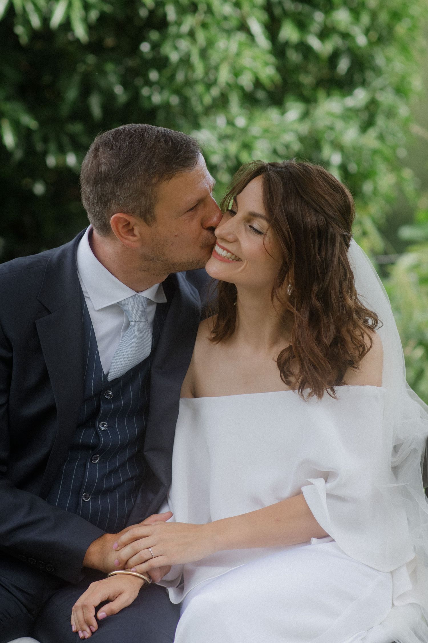 Romantic wedding portrait showing tender moment between couple in garden setting.