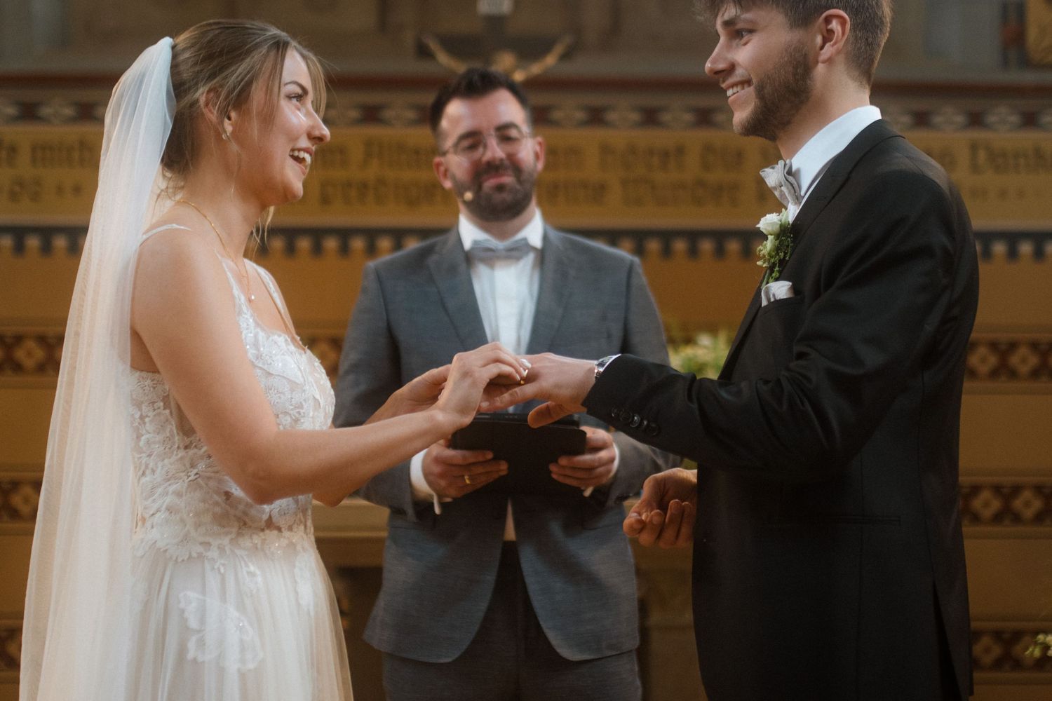 Couple exchanging rings during traditional church wedding ceremony.