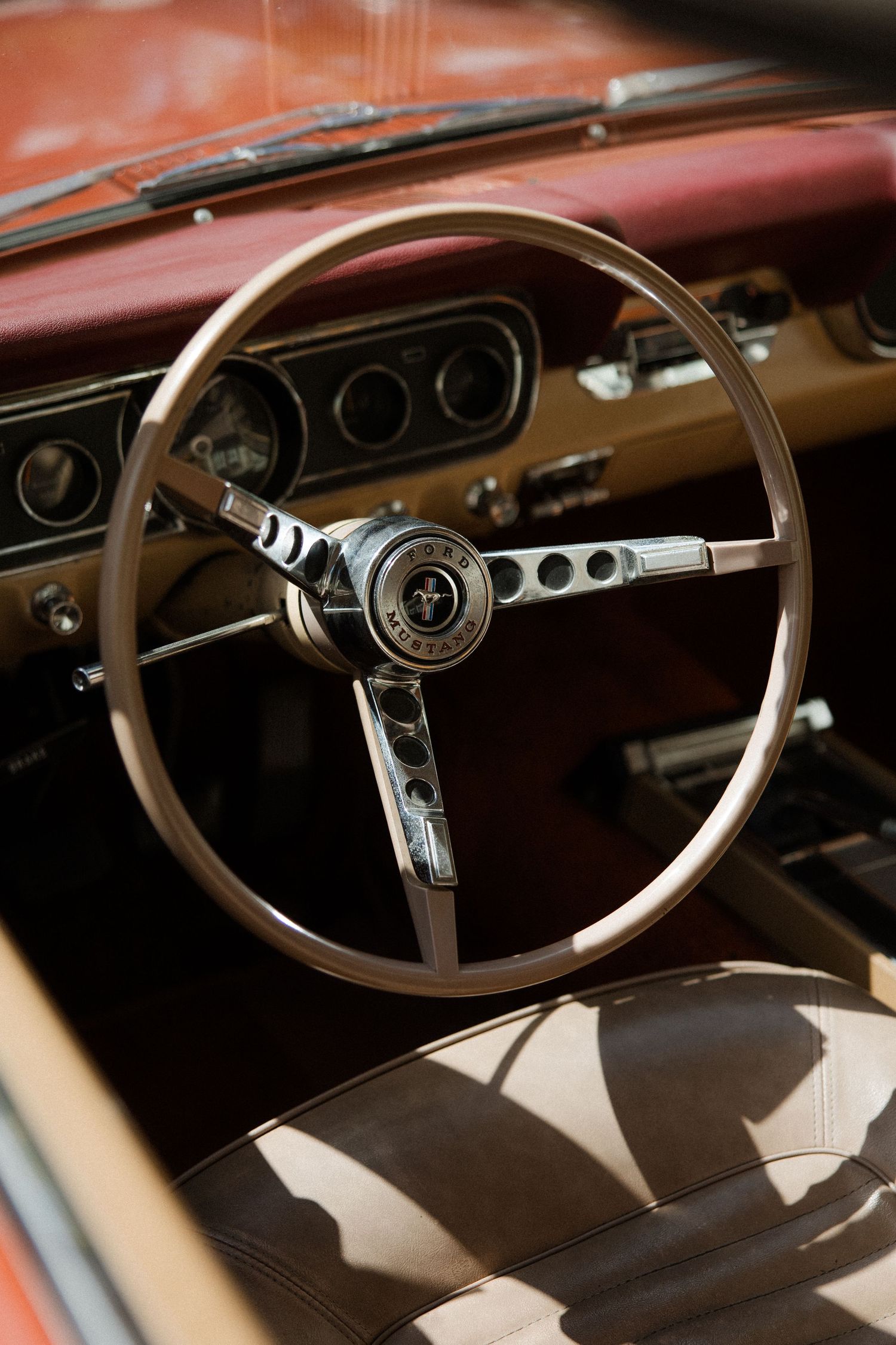 Classic Ford Mustang steering wheel and dashboard interior in brown leather and chrome.
