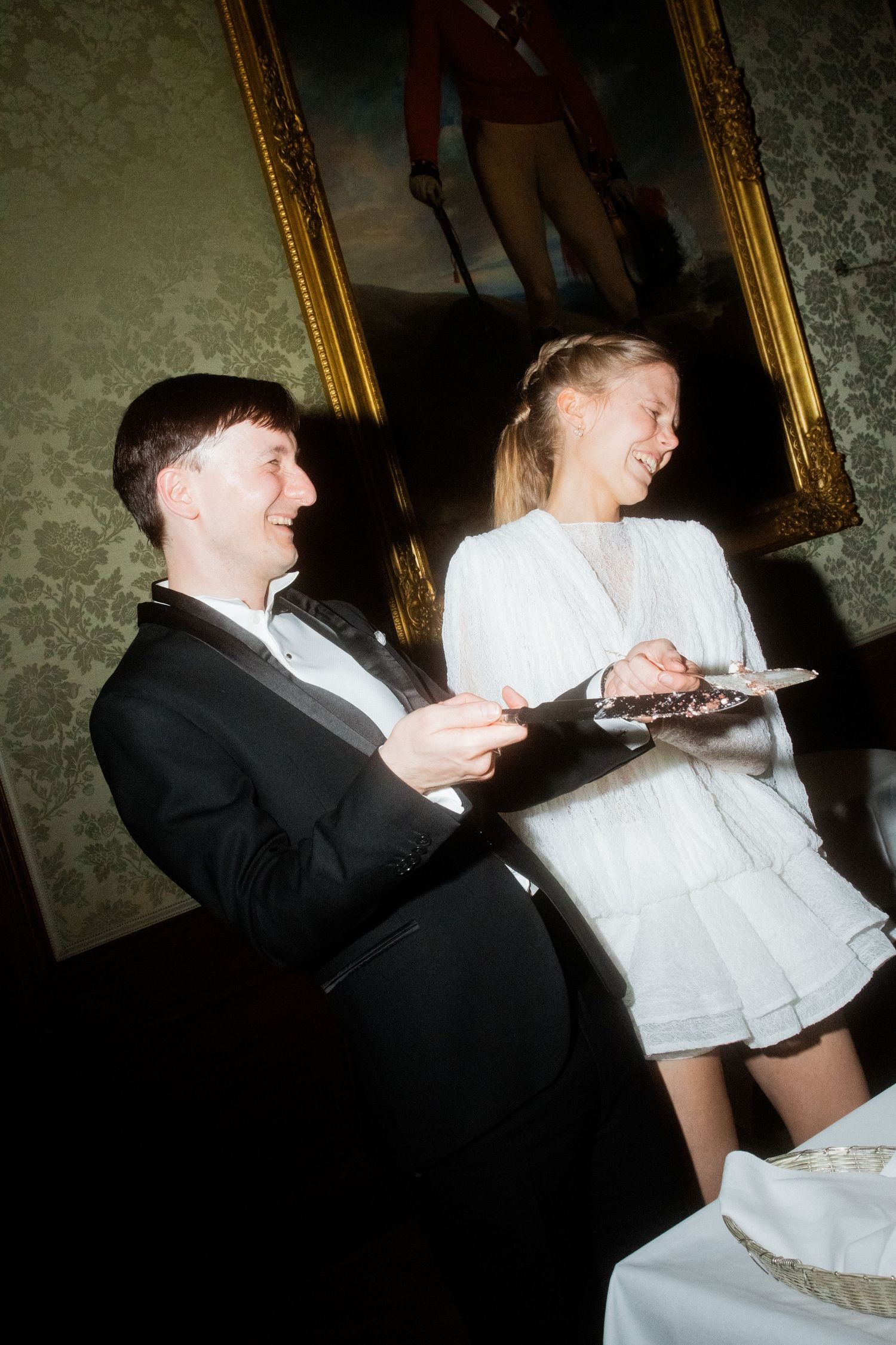 A couple shares a playful moment during their wedding dance, with the groom dipping the bride in a white dress.