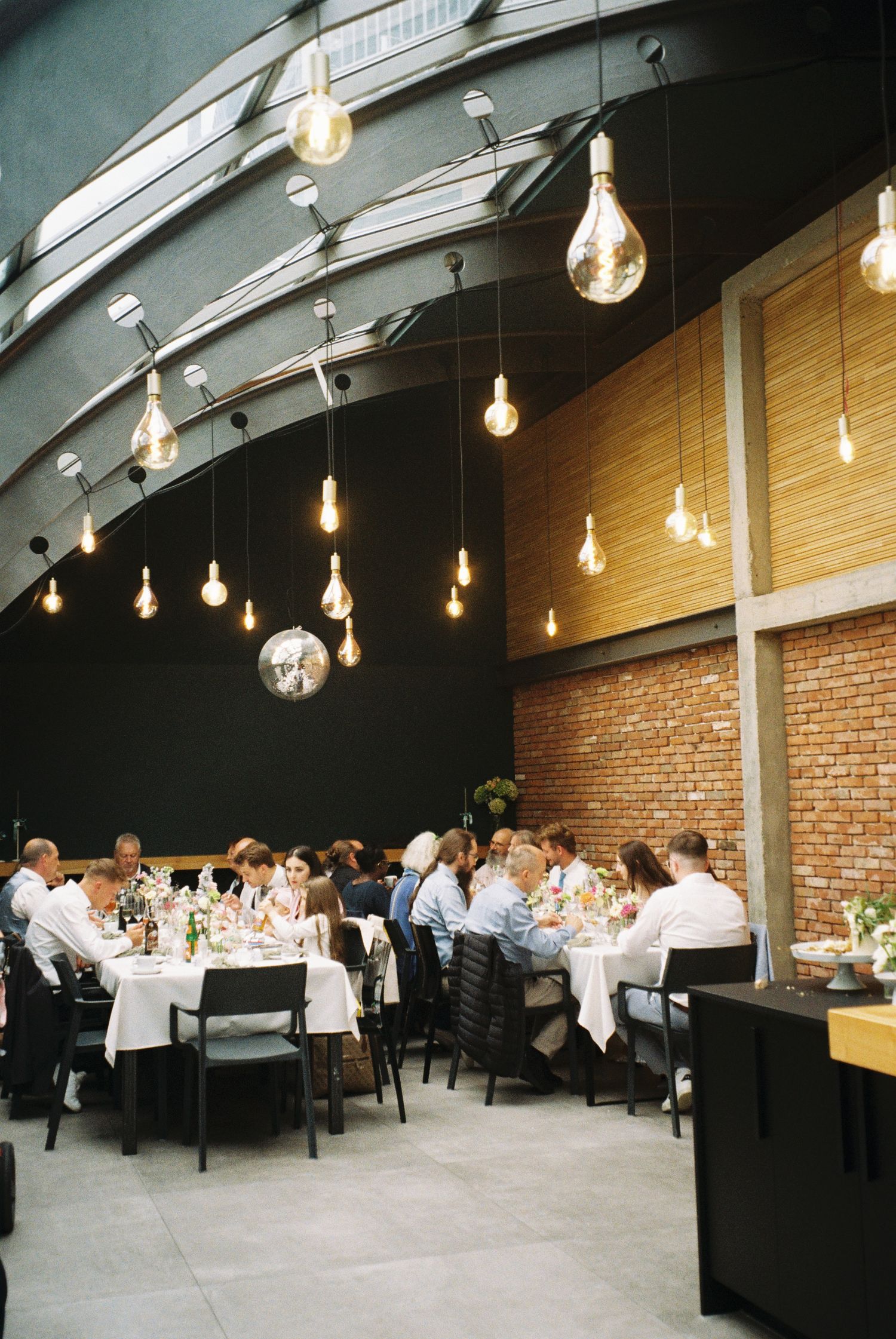 Modern restaurant interior with exposed brick walls, string lights, and angled ceiling creates an inviting dining atmosphere.