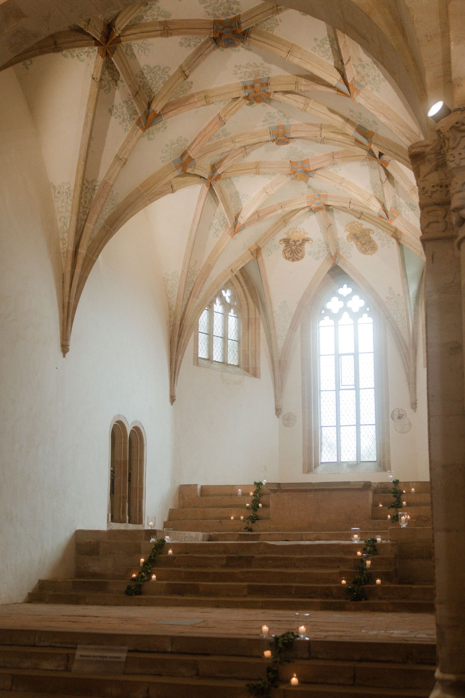 Gothic church interior with vaulted ceiling, wooden pews, and candlelit steps creating a romantic atmosphere.