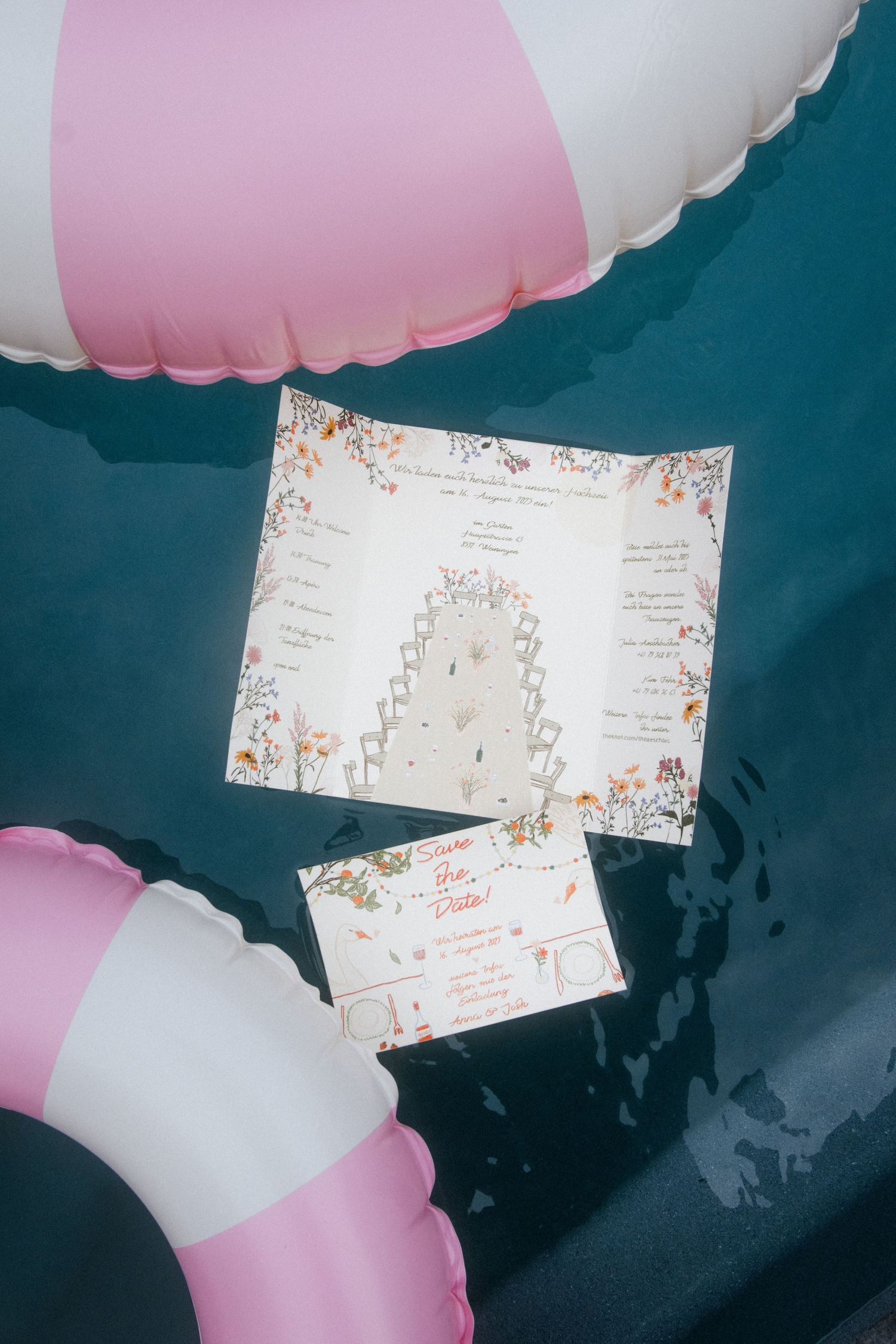 Wedding invitation and RSVP card with floral design surrounded by pink pool floats.