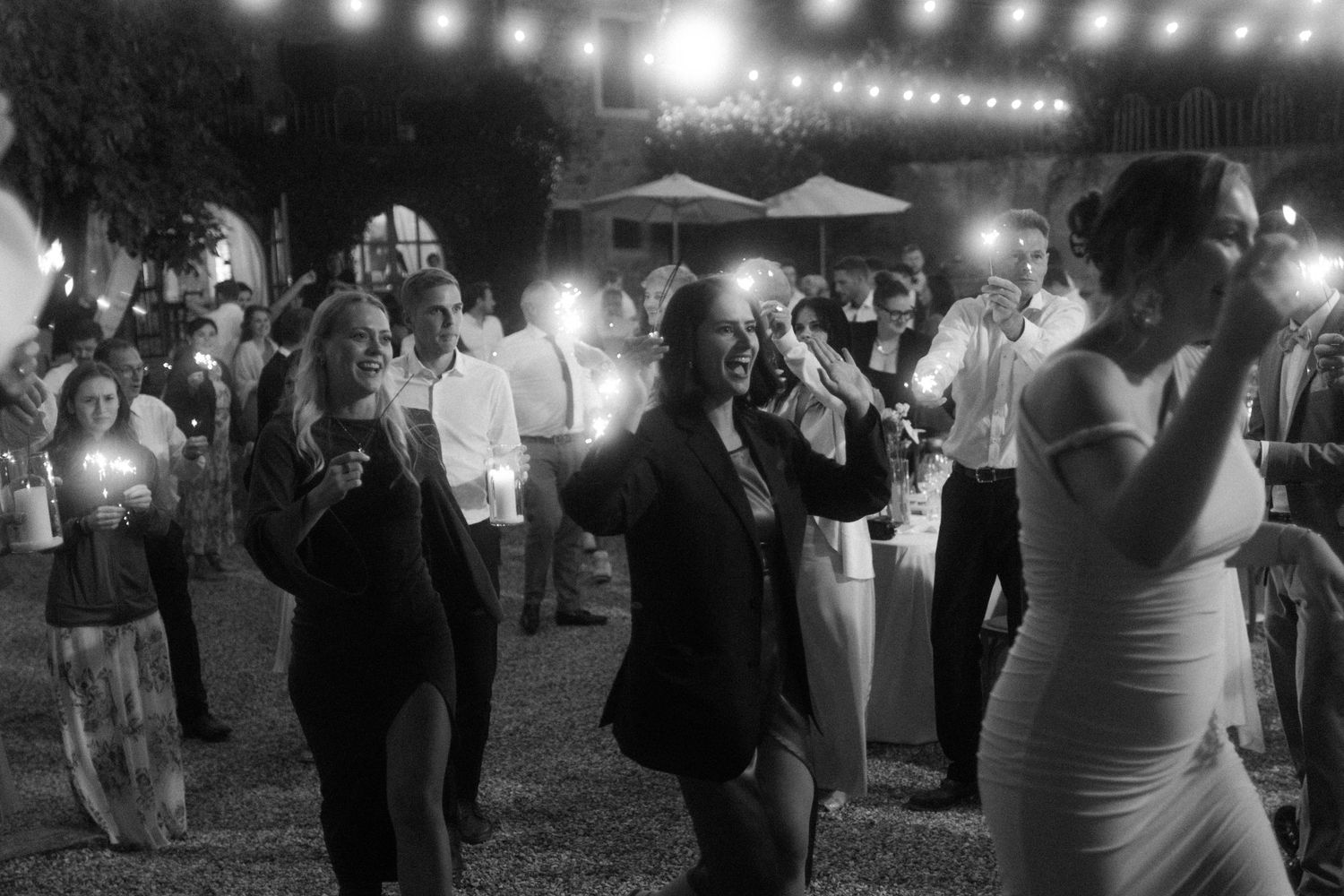 Guests dance and celebrate at a wedding reception under string lights.