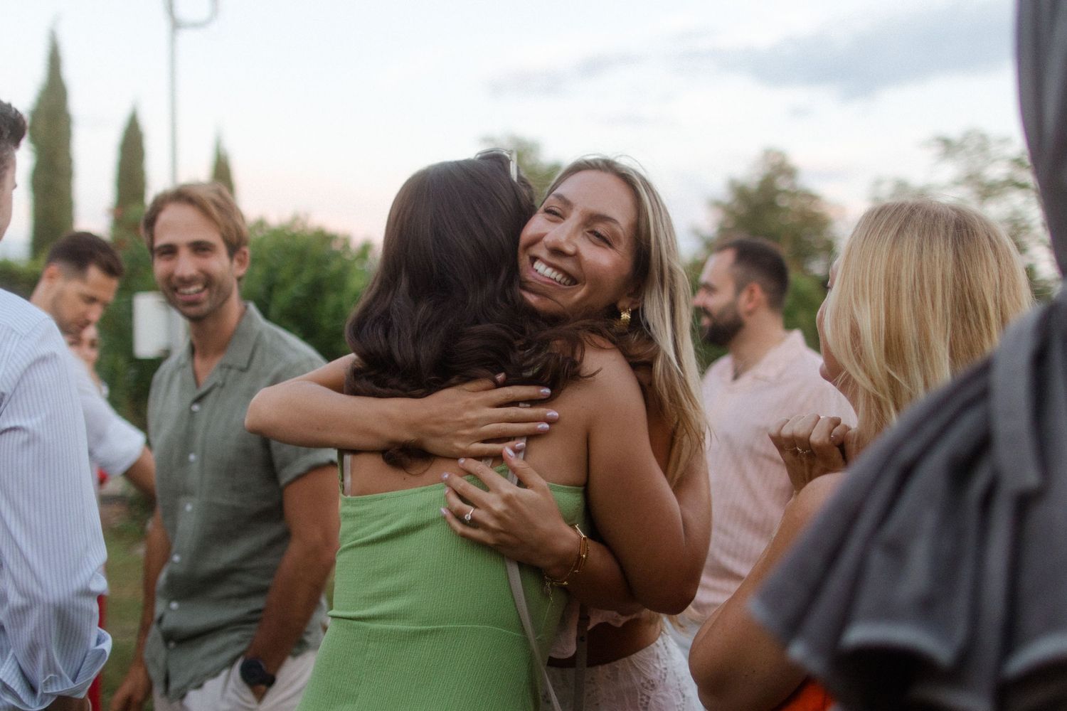 A group of guests enjoying themselves at an outdoor celebration with string lights in the background.