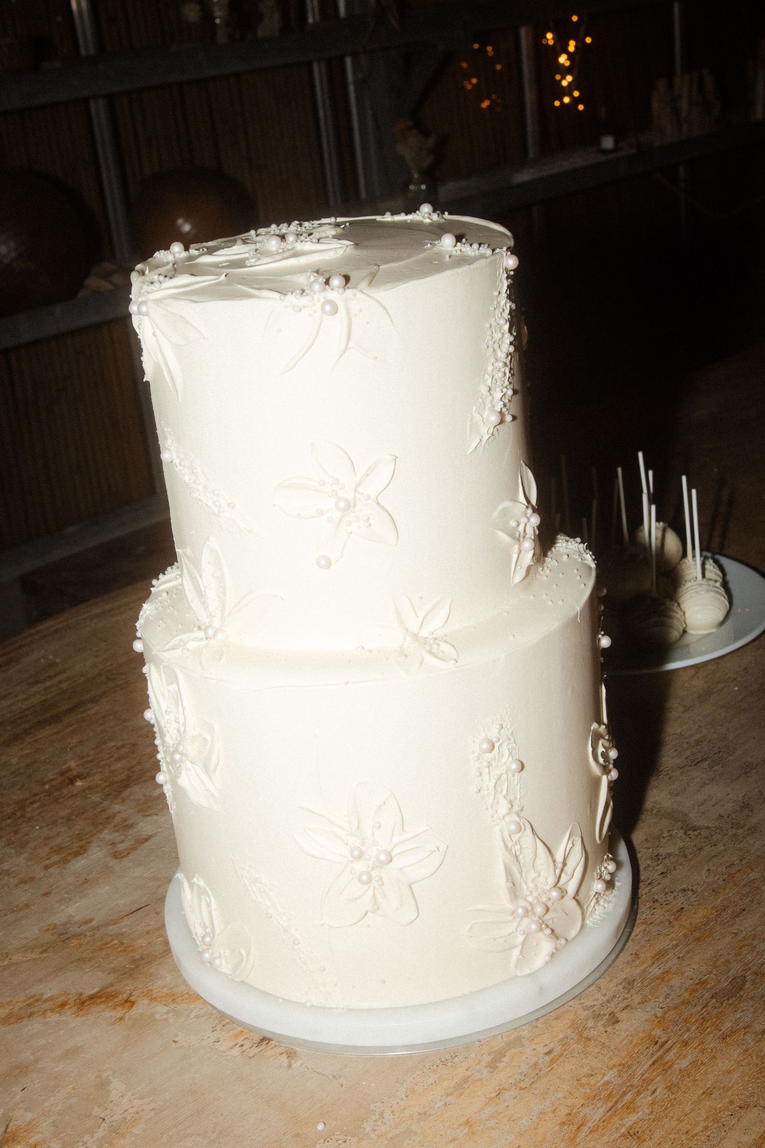Elegant two-tier white wedding cake with delicate floral details.