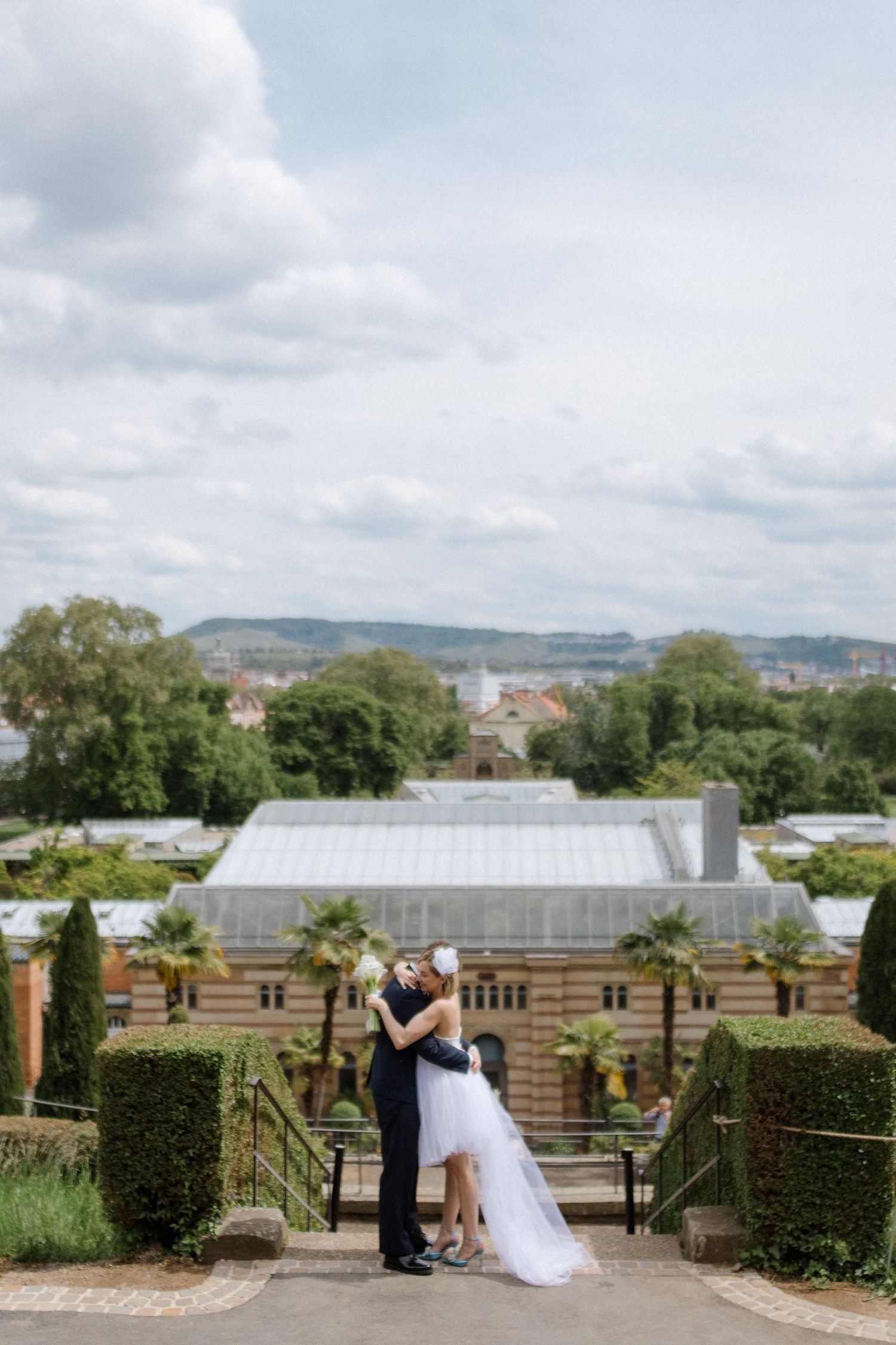 Garden wedding scene overlooking a greenhouse and cityscape on a cloudy day.
