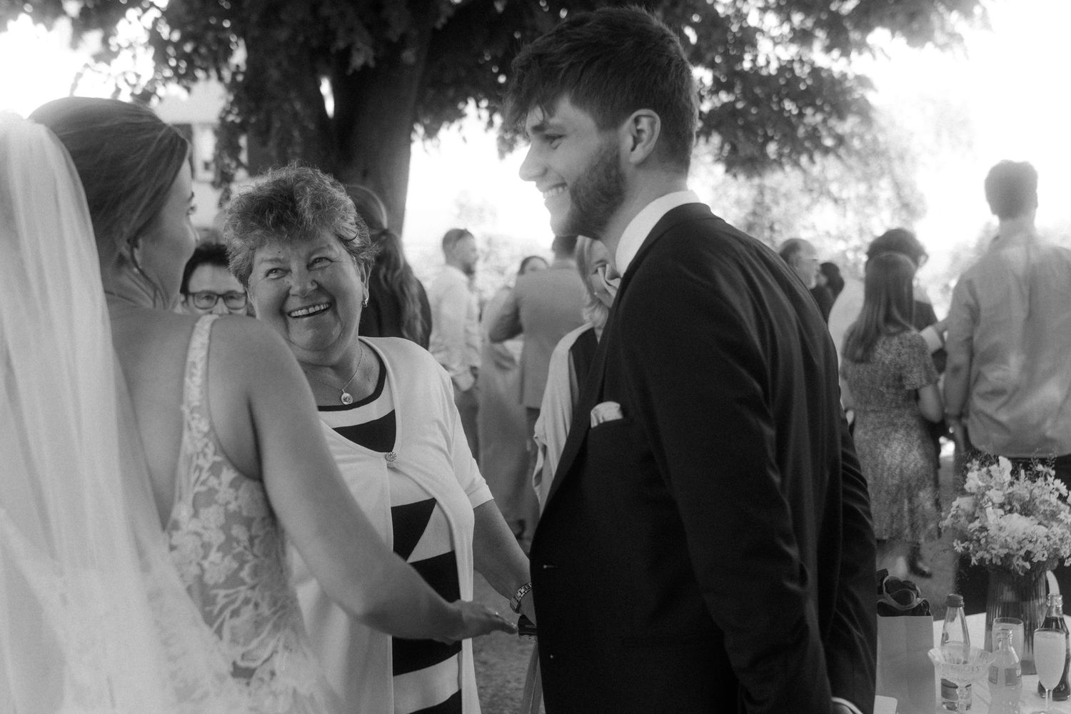 Black and white candid moment of joyful laughter during outdoor wedding ceremony.