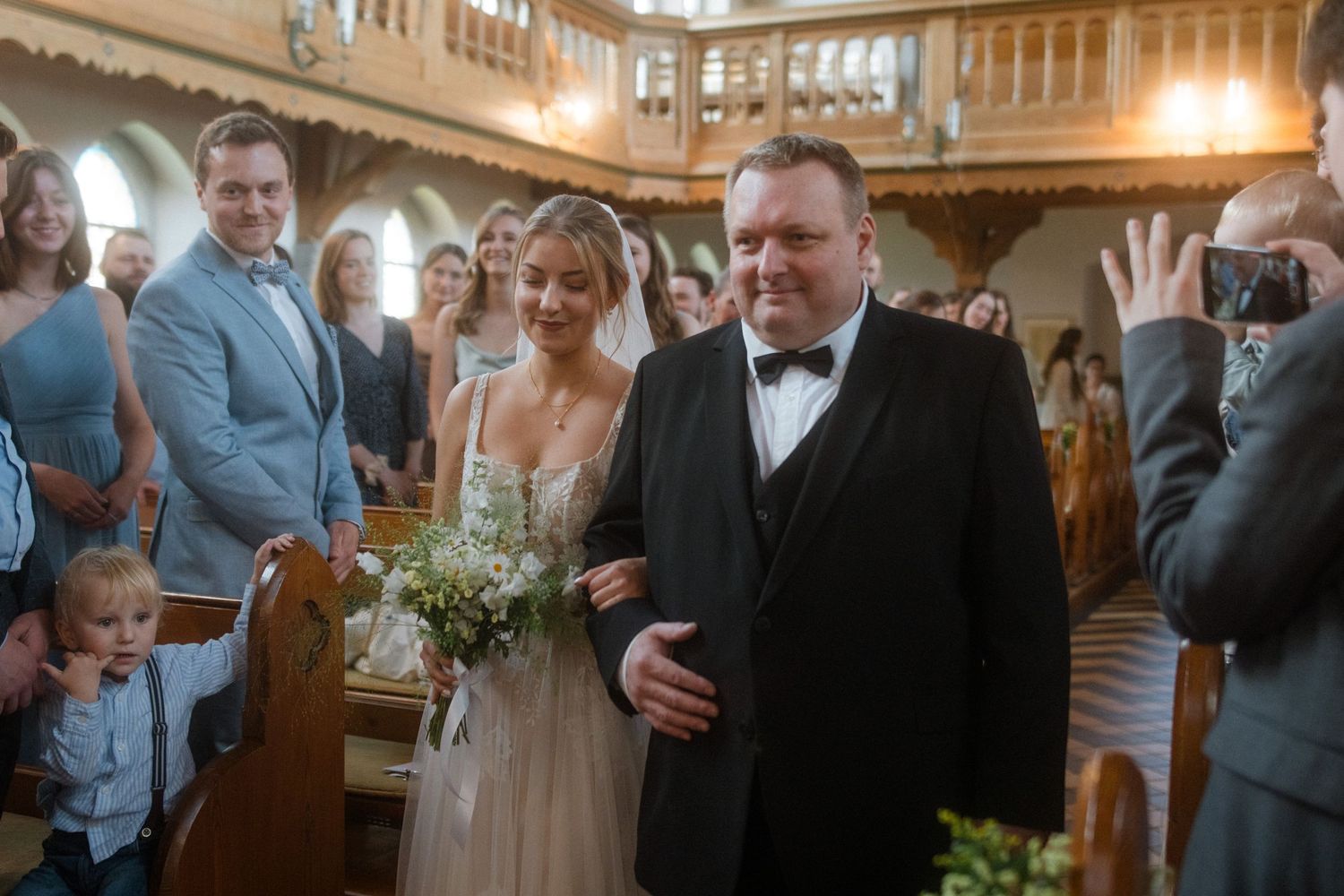 A wedding ceremony in progress inside a historic church with wooden pews and decorative architecture.