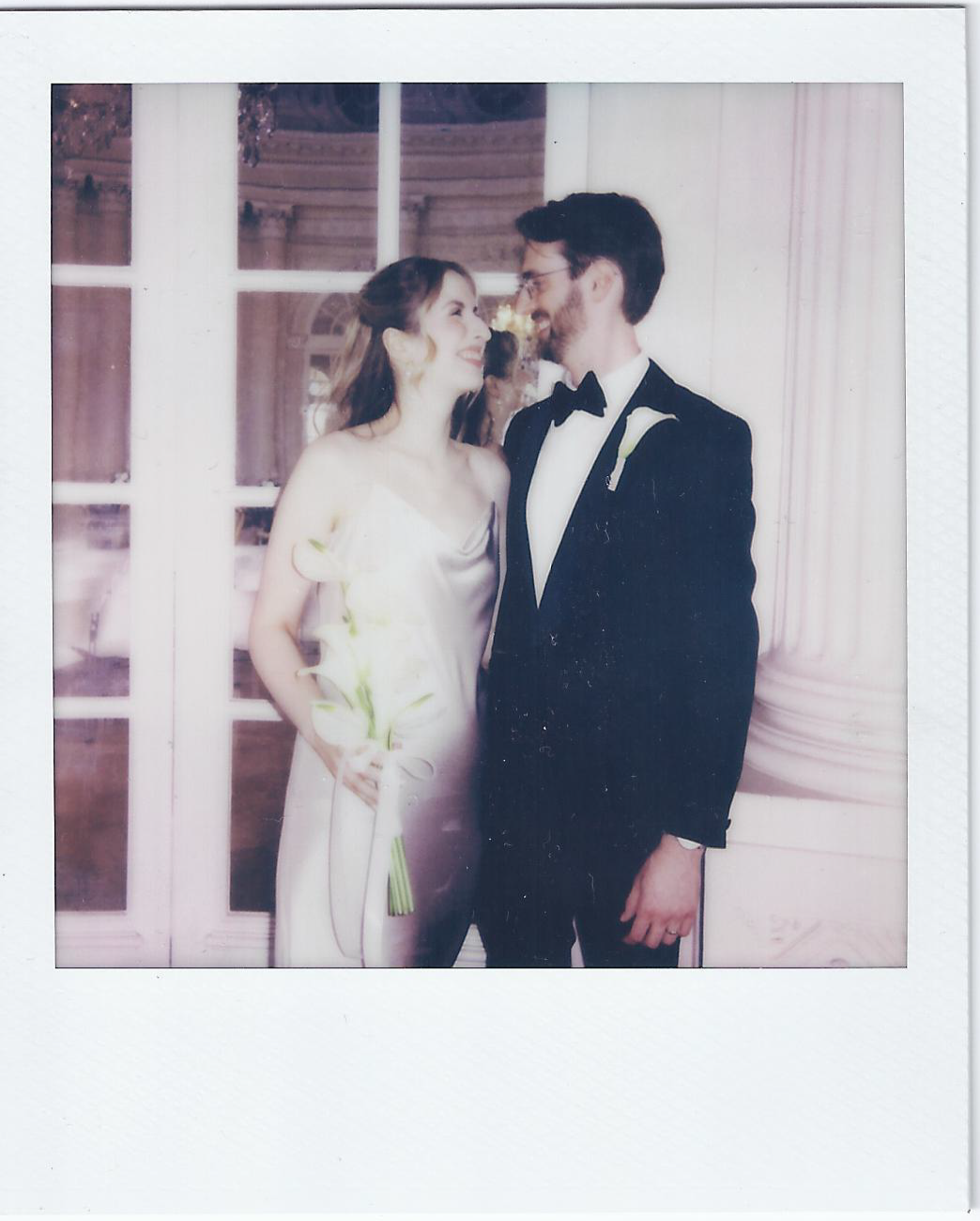 A romantic polaroid-style wedding photo of a couple in formal attire.