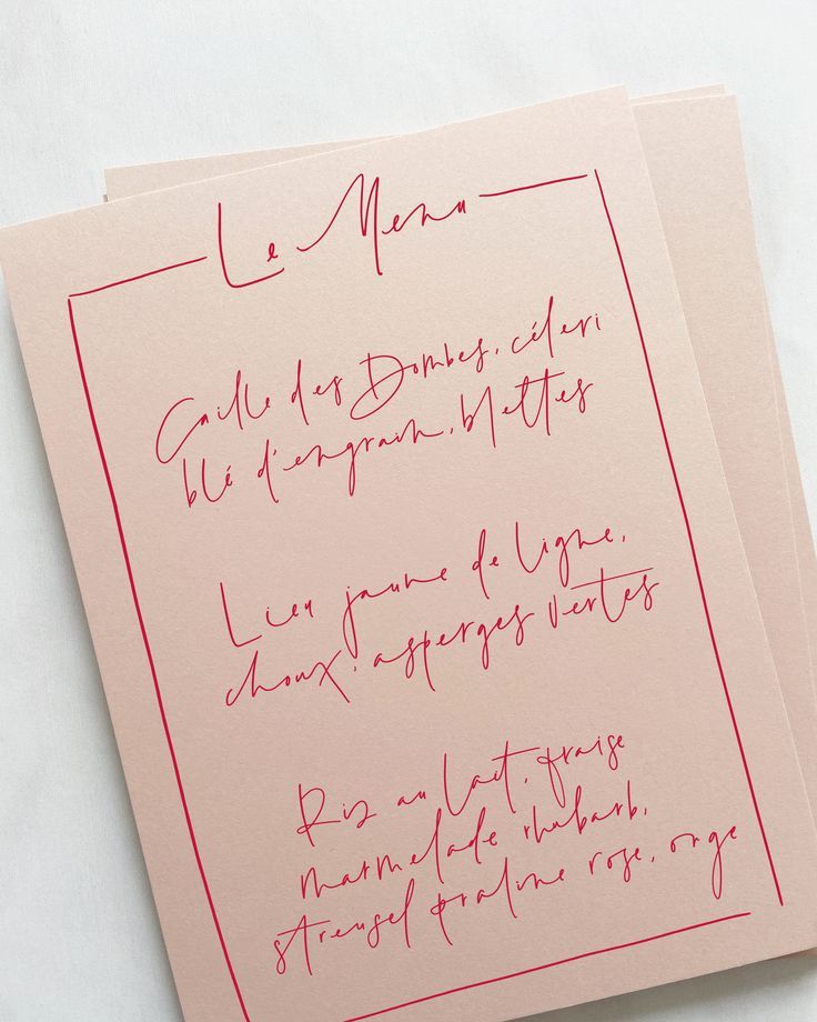 Elegant wedding menu card with red handwritten calligraphy on blush paper.