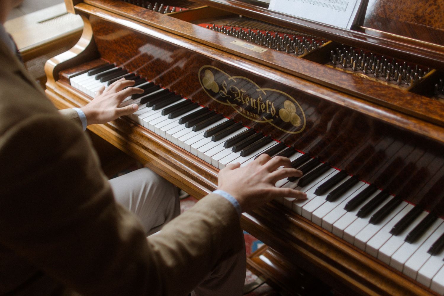 Close-up of hands playing a grand piano in dramatic lighting.