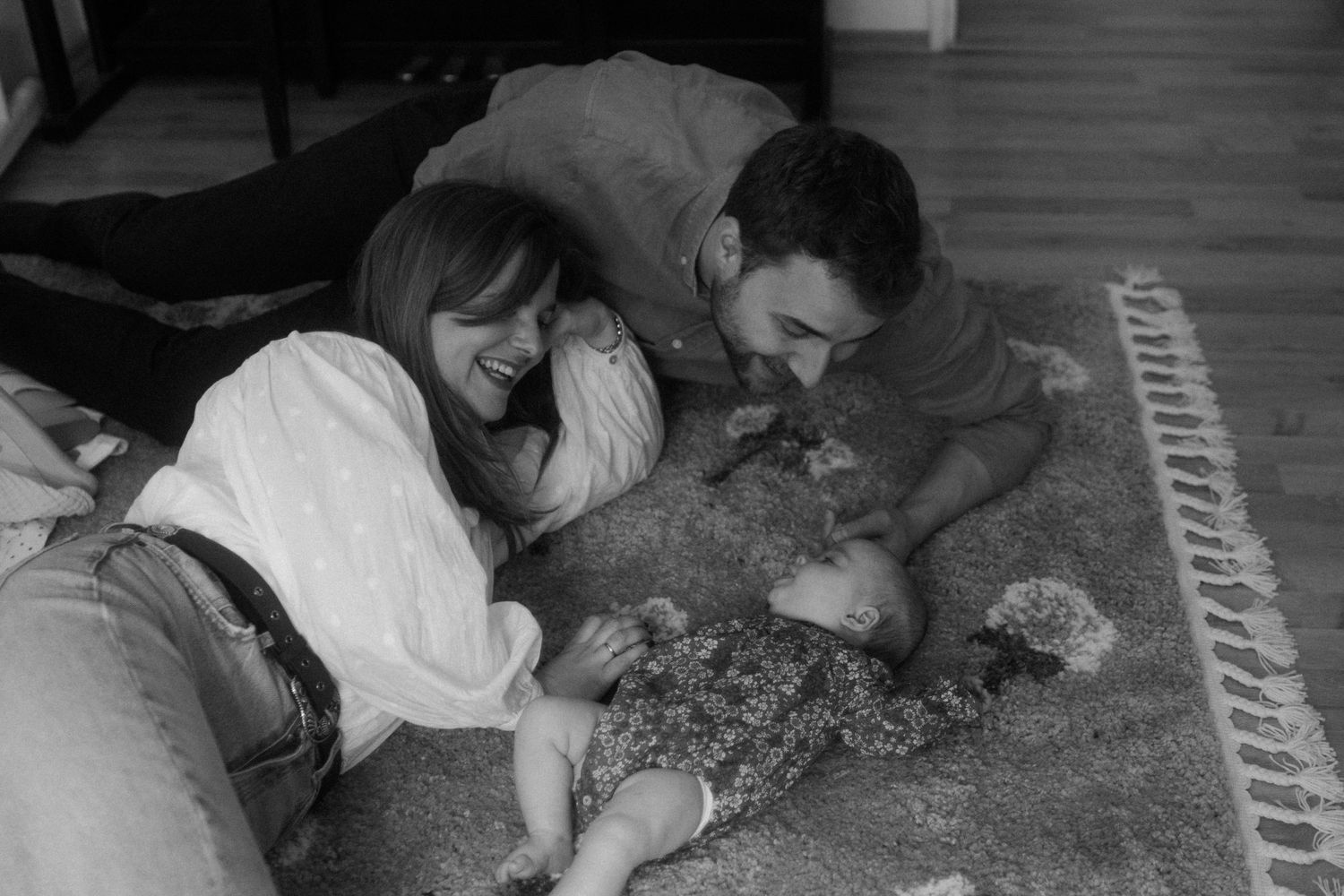 Family relaxing together on carpet floor in black and white photography.