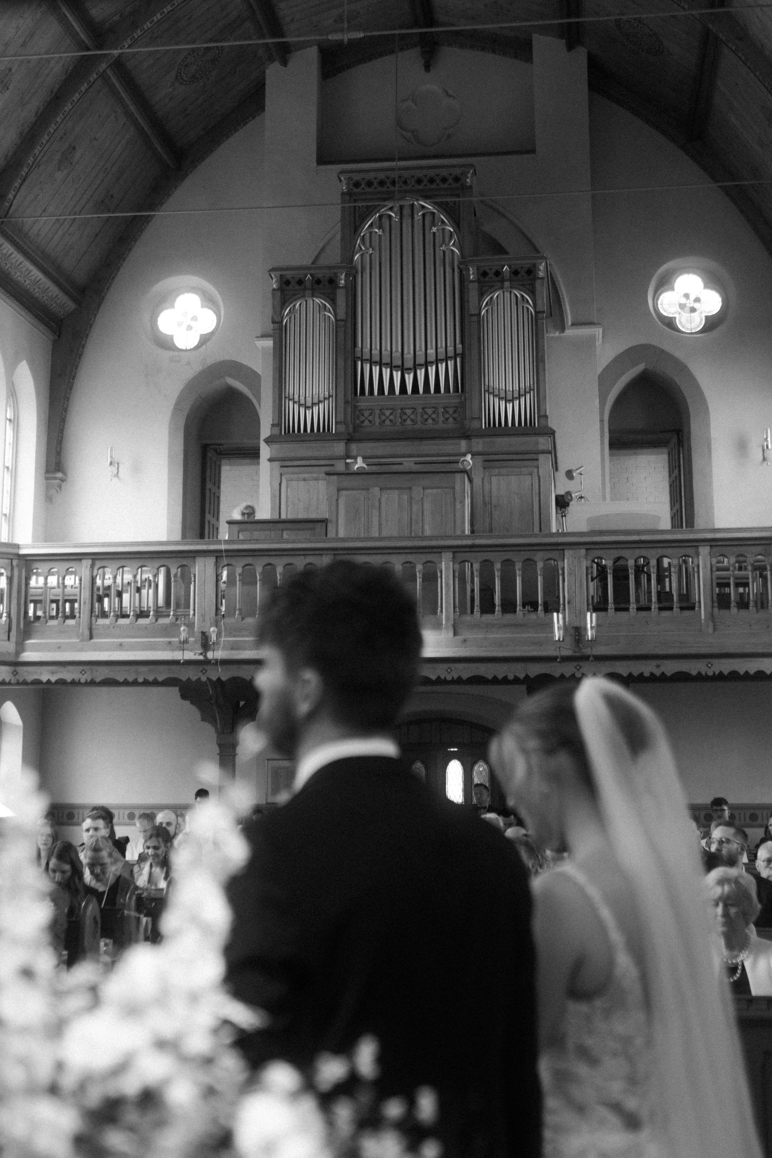 Black and white photo of a wedding ceremony in a church with a prominent pipe organ in the background.