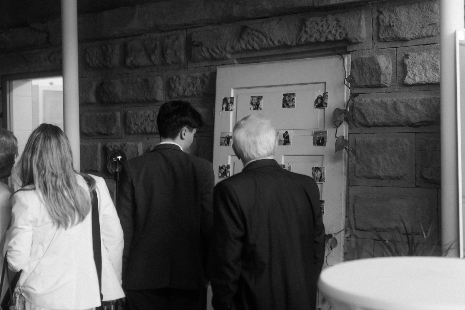 People viewing photographs displayed on a stone wall at an event.