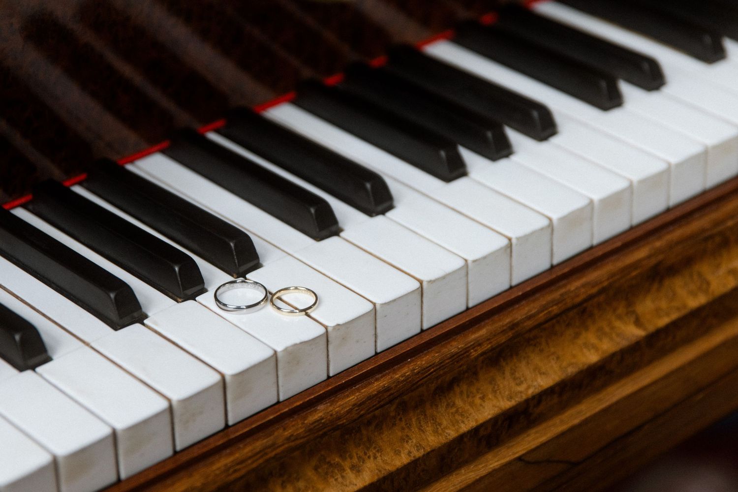 Wedding rings placed on black and white piano keys in romantic composition.