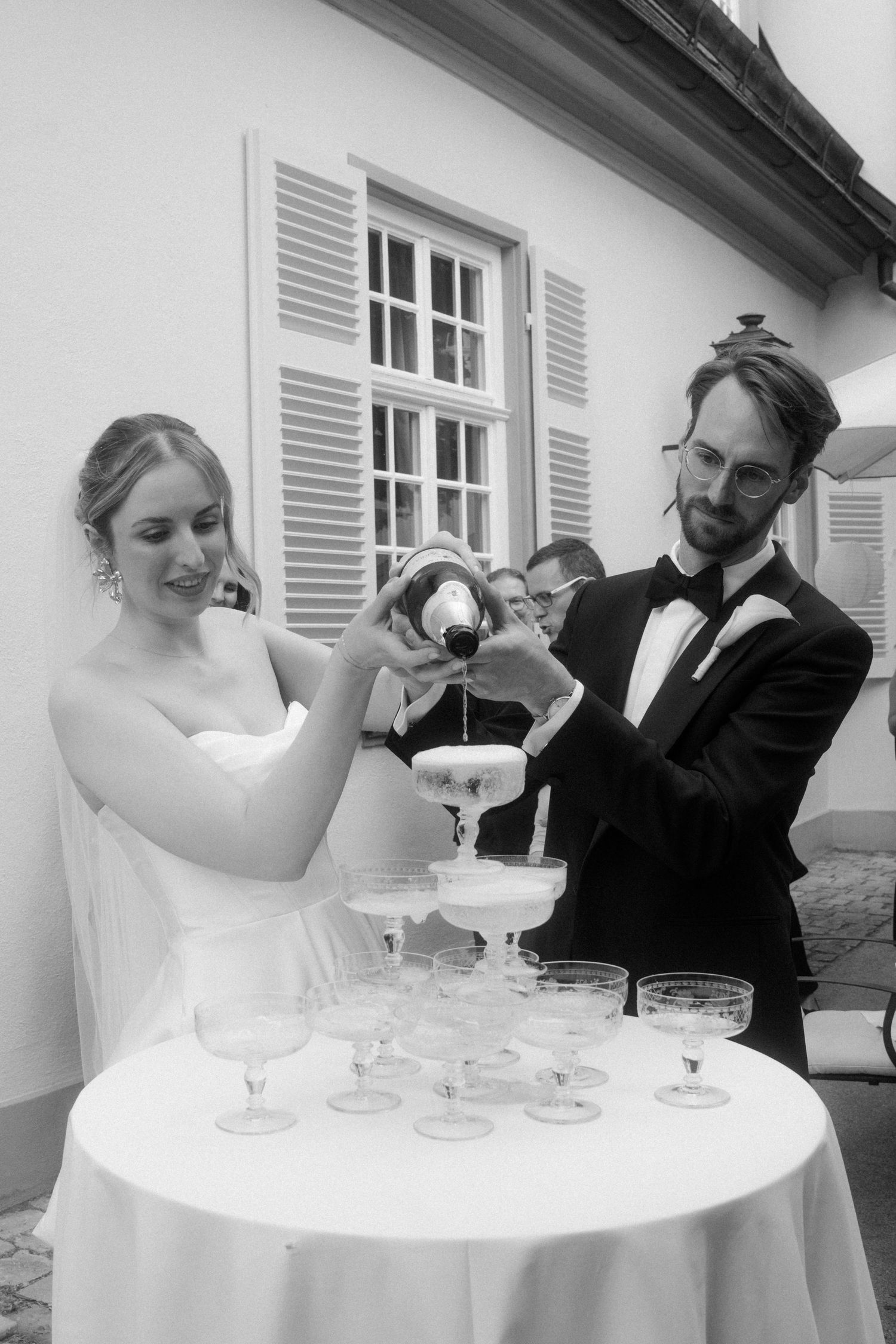 A couple creating a champagne tower at their wedding celebration.
