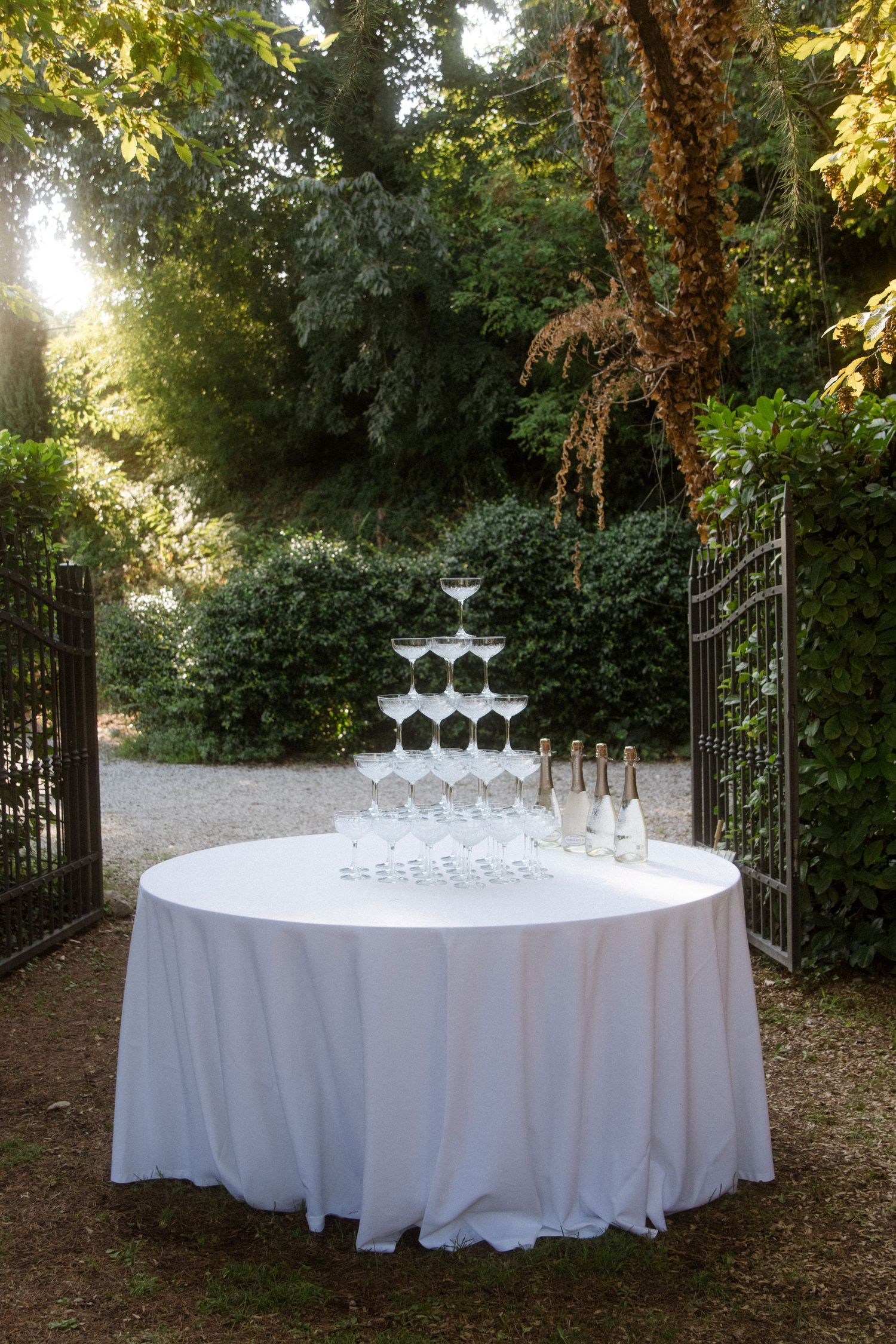Elegant round table with champagne glasses set up in garden setting.