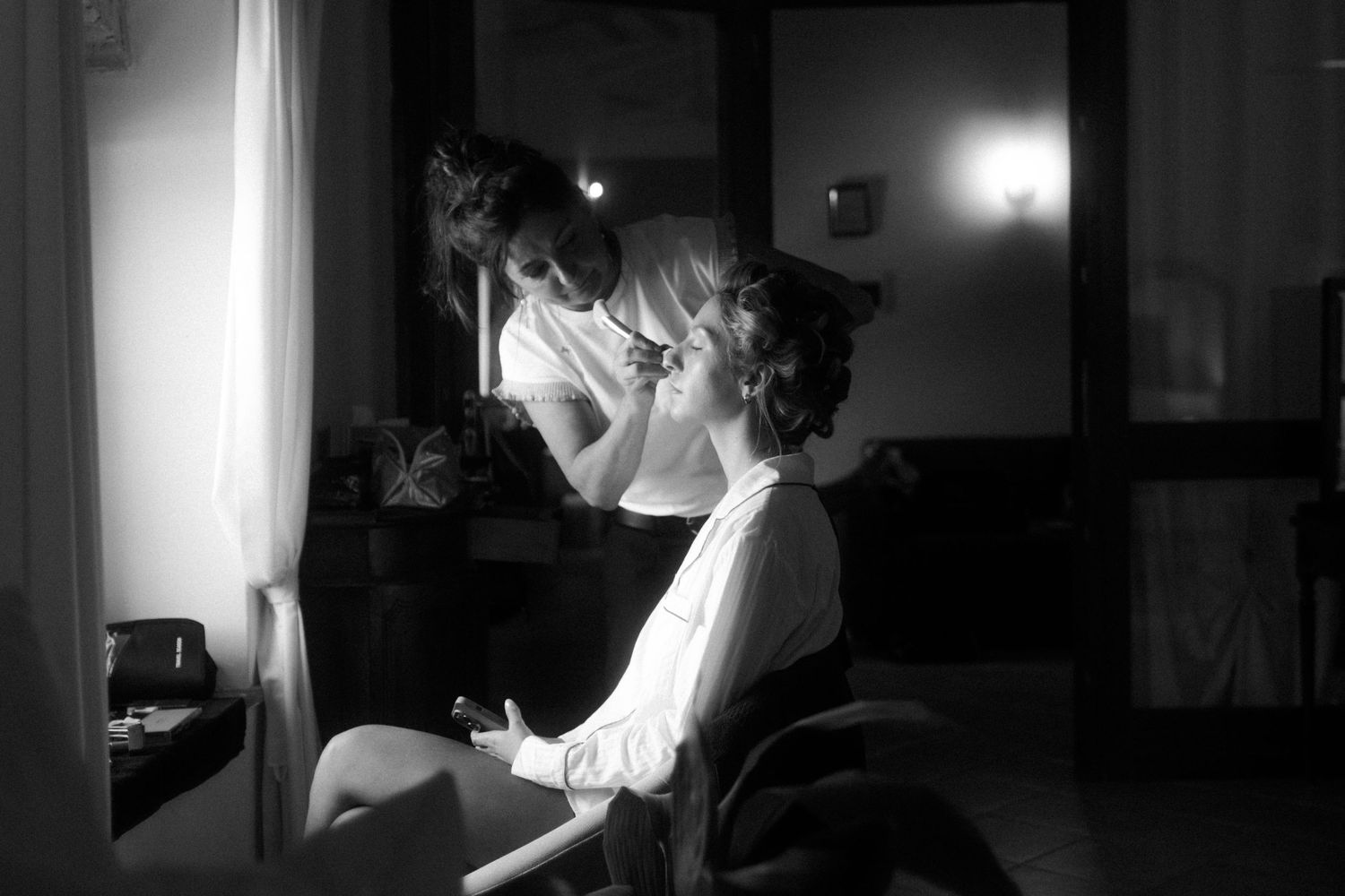 A dramatic black and white series of photographs showing someone adjusting a tie in dim lighting.