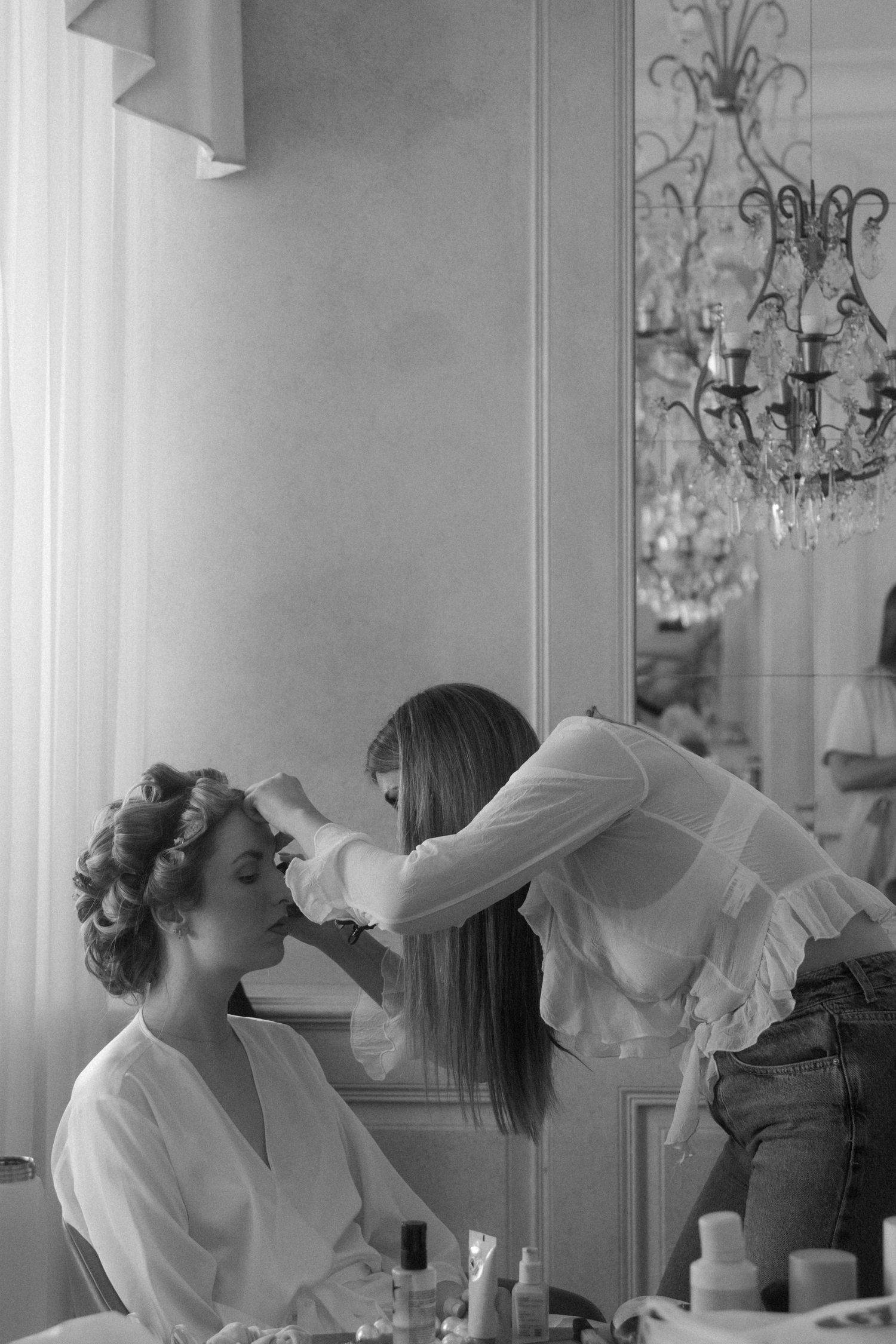A series of black and white photos showing hair styling under a crystal chandelier.